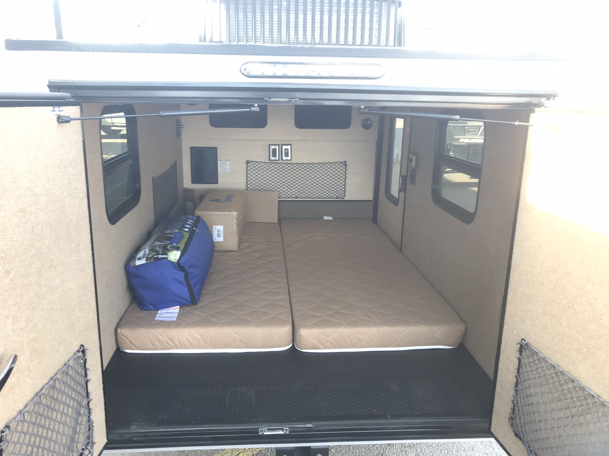 RV rental: Inside a compact camper, featuring two mattresses, side windows, and storage nets on the walls.. Intech Flyer 2017