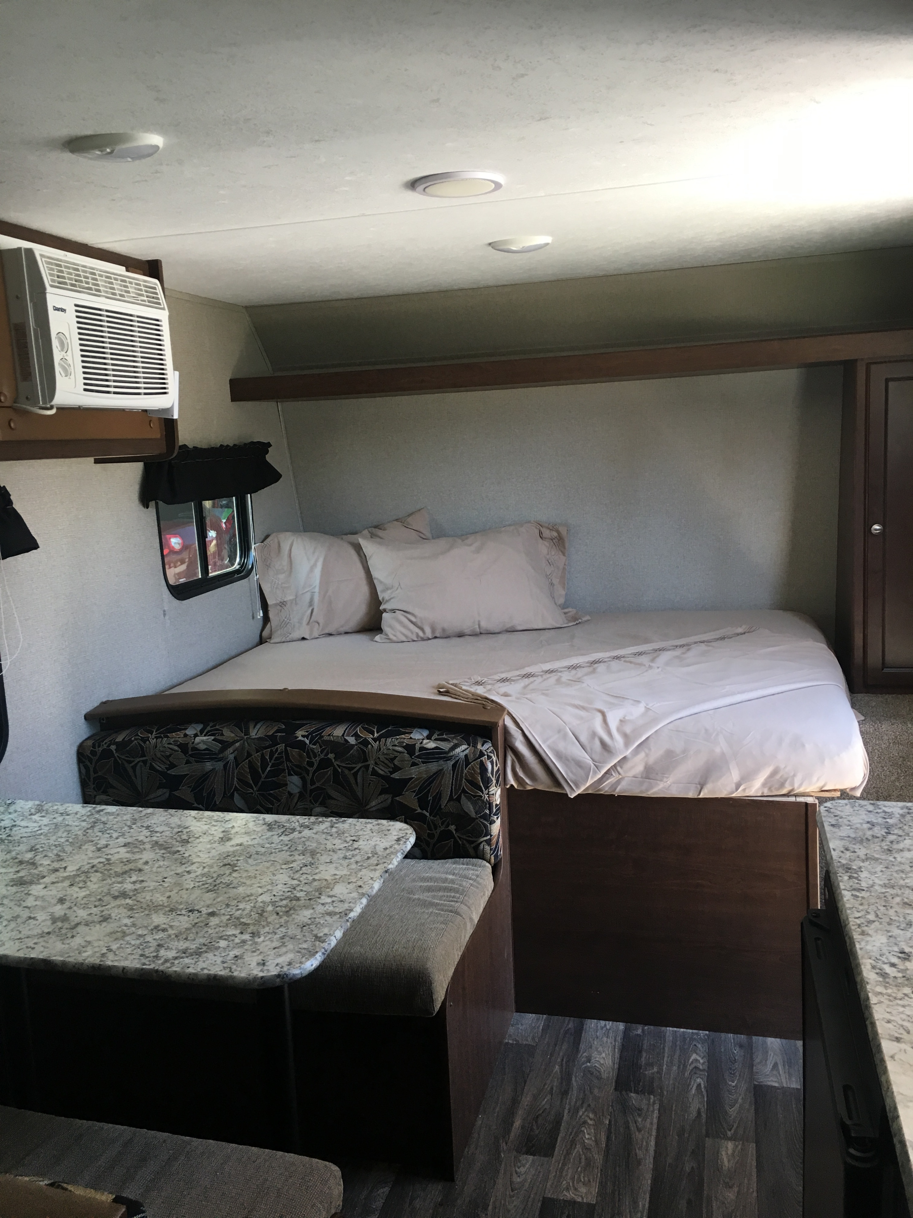 Cozy RV rental interior featuring a bed, dining nook, and AC unit. Compact and functional space.. Keystone Hideout 2017