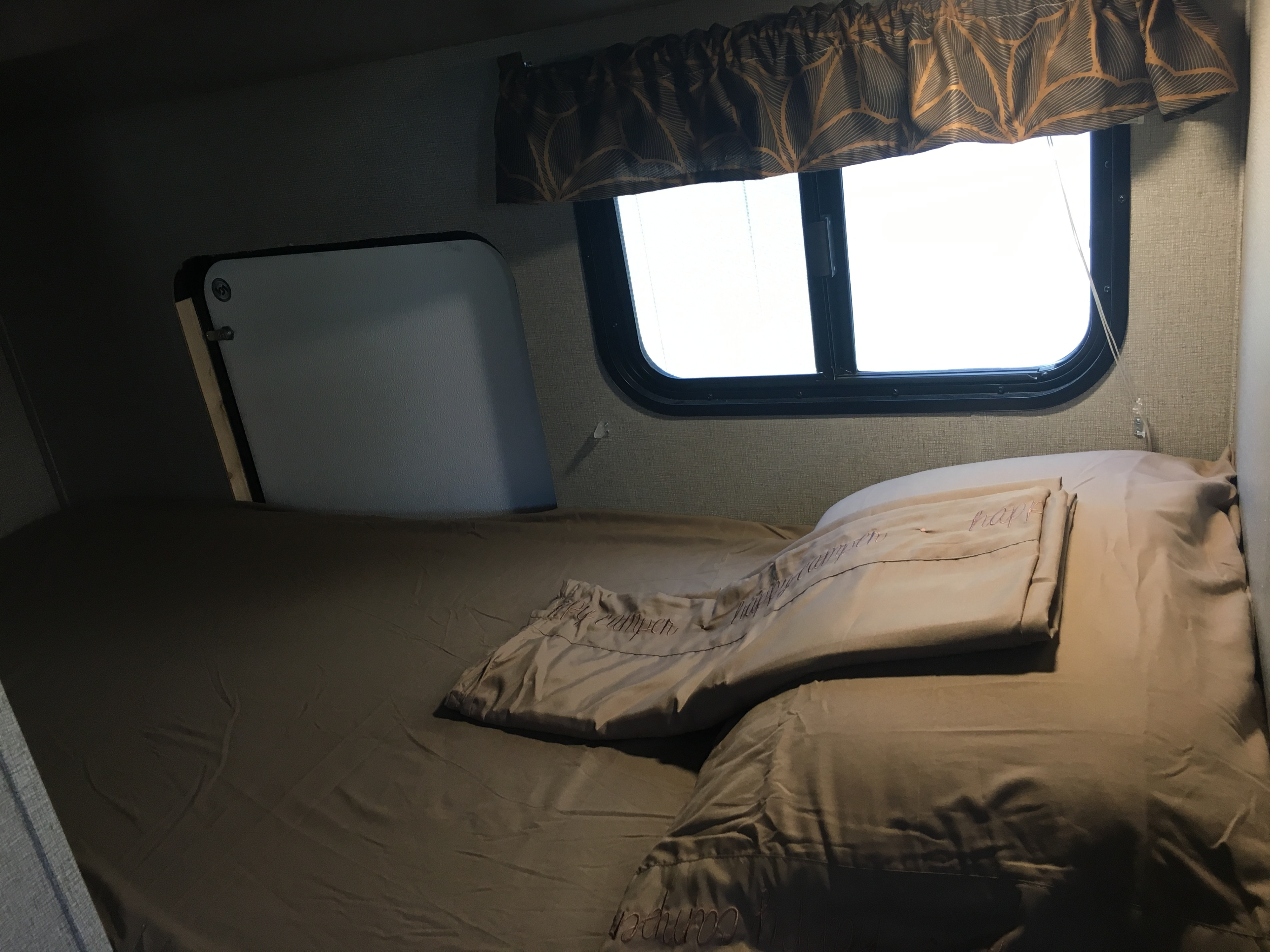RV rental sleeping area: Cozy bed with "Happy Camper" bedding and bright window.. Keystone Hideout 2017