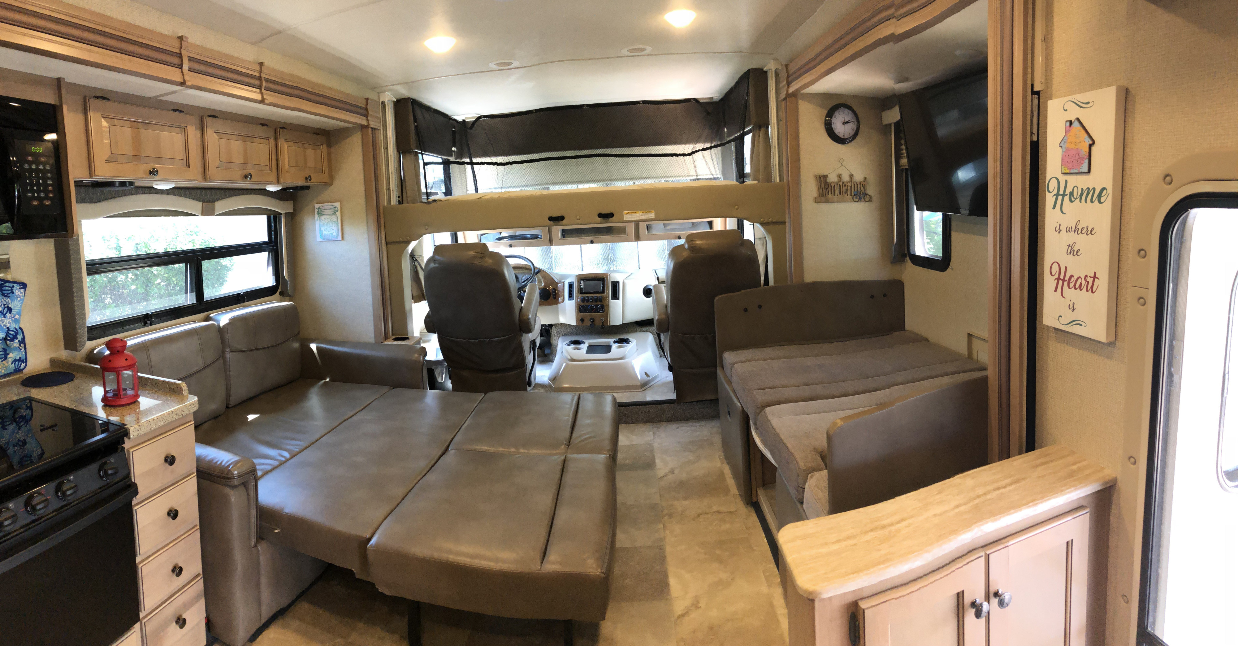 Spacious RV rental interior featuring kitchen, sofa bed, dining booth, driver's cabin, and overhead bunk.. Thor Windsport 2018