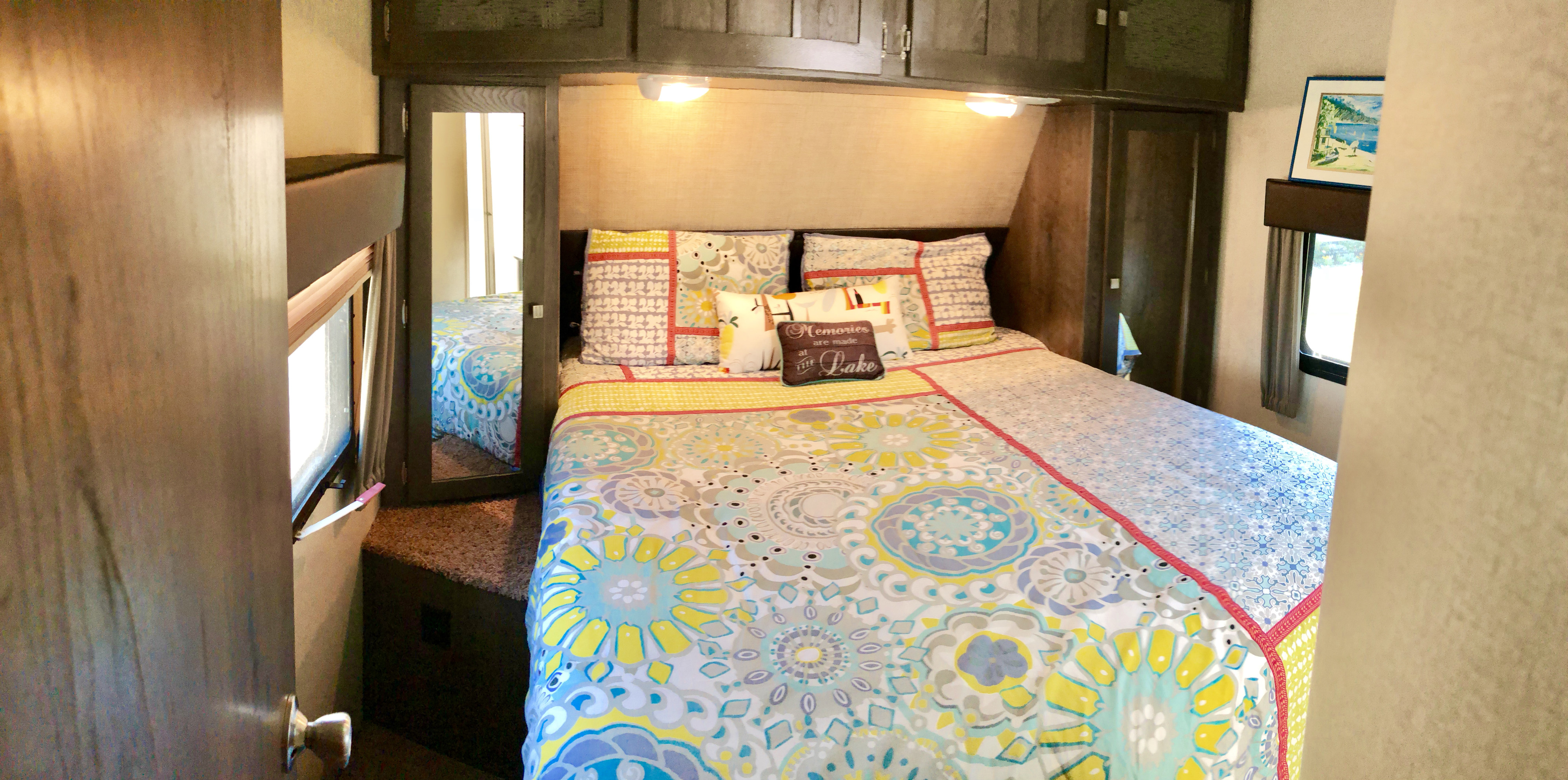 Cozy RV rental bedroom with vibrant bedding, overhead cabinets, and a mirrored closet. Perfect for your travels.. Dutchman Kodiak 300bhsl 2015