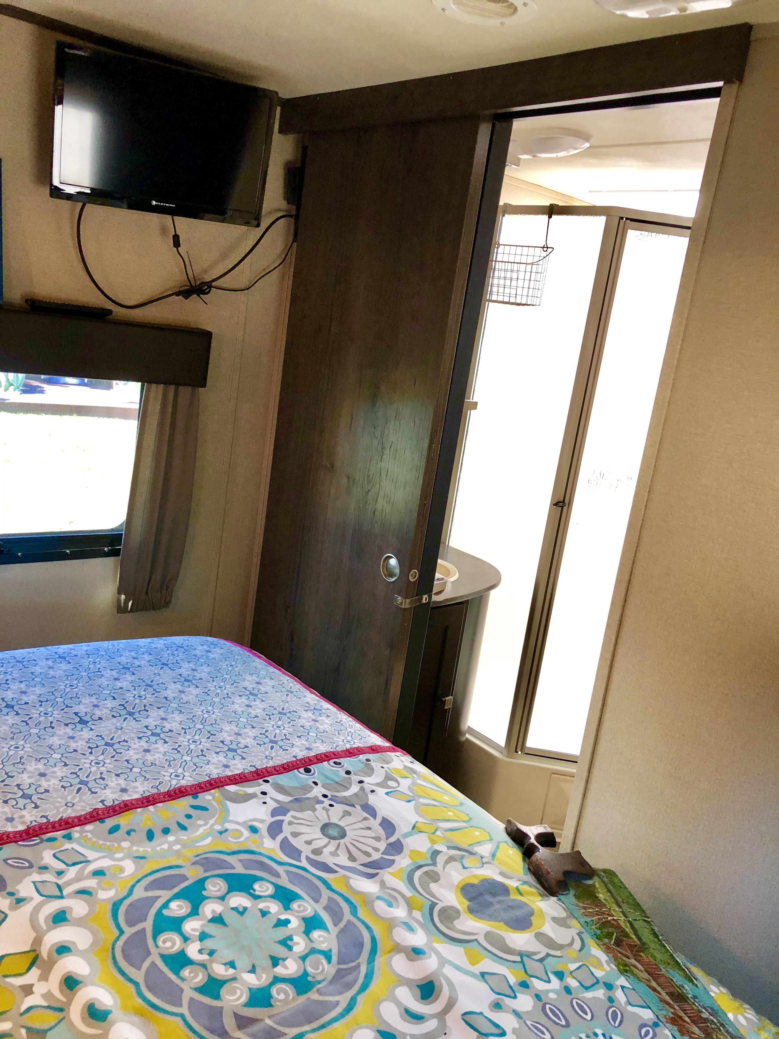 Cozy RV rental bedroom with TV, colorful bedding, and sliding door to the bathroom.. Dutchman Kodiak 300bhsl 2015