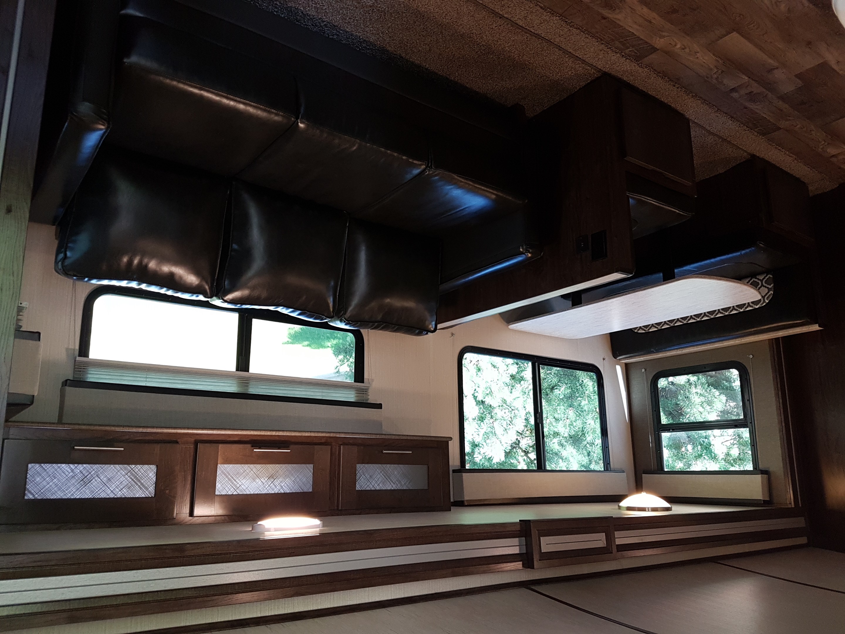 Spacious RV rental interior with comfy seating, modern wood cabinetry, and large windows showing lush greenery.. Cruiser Rv Corp Radiance 2019