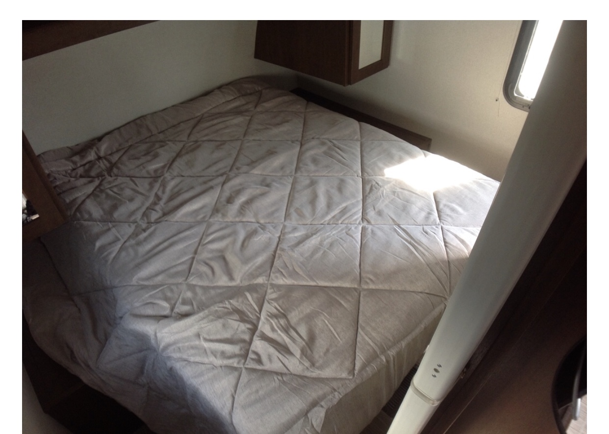 Cozy RV rental bedroom with a quilted bed, bathed in natural light. Perfect for a comfortable night's sleep on the road.. Forest River Tracer 2019