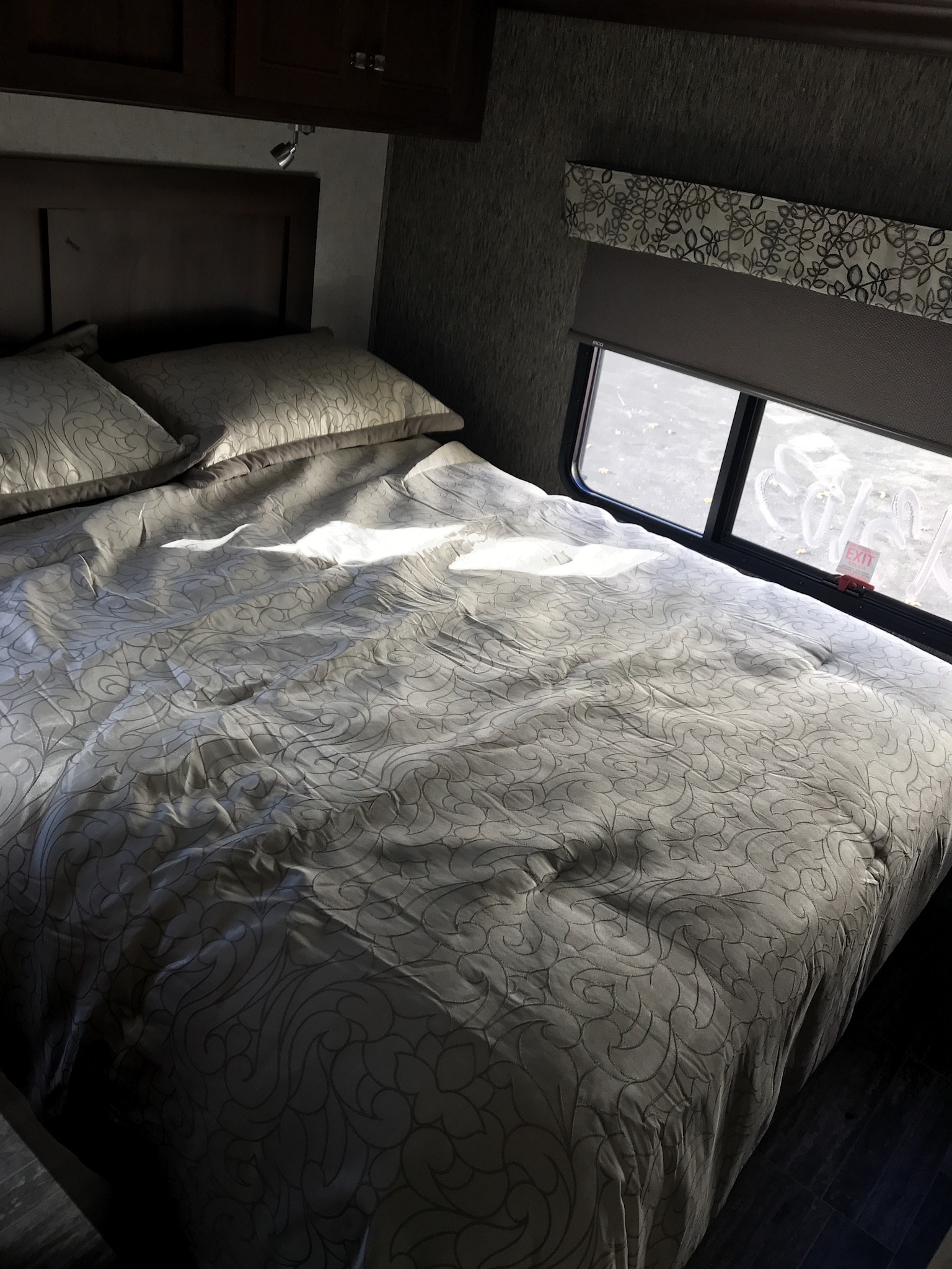 Inside an RV rental: a bright, comfortable bedroom with a patterned bed, pillows, and an emergency exit window. Perfect for your next adventure.. Forester 3271 LE 2018