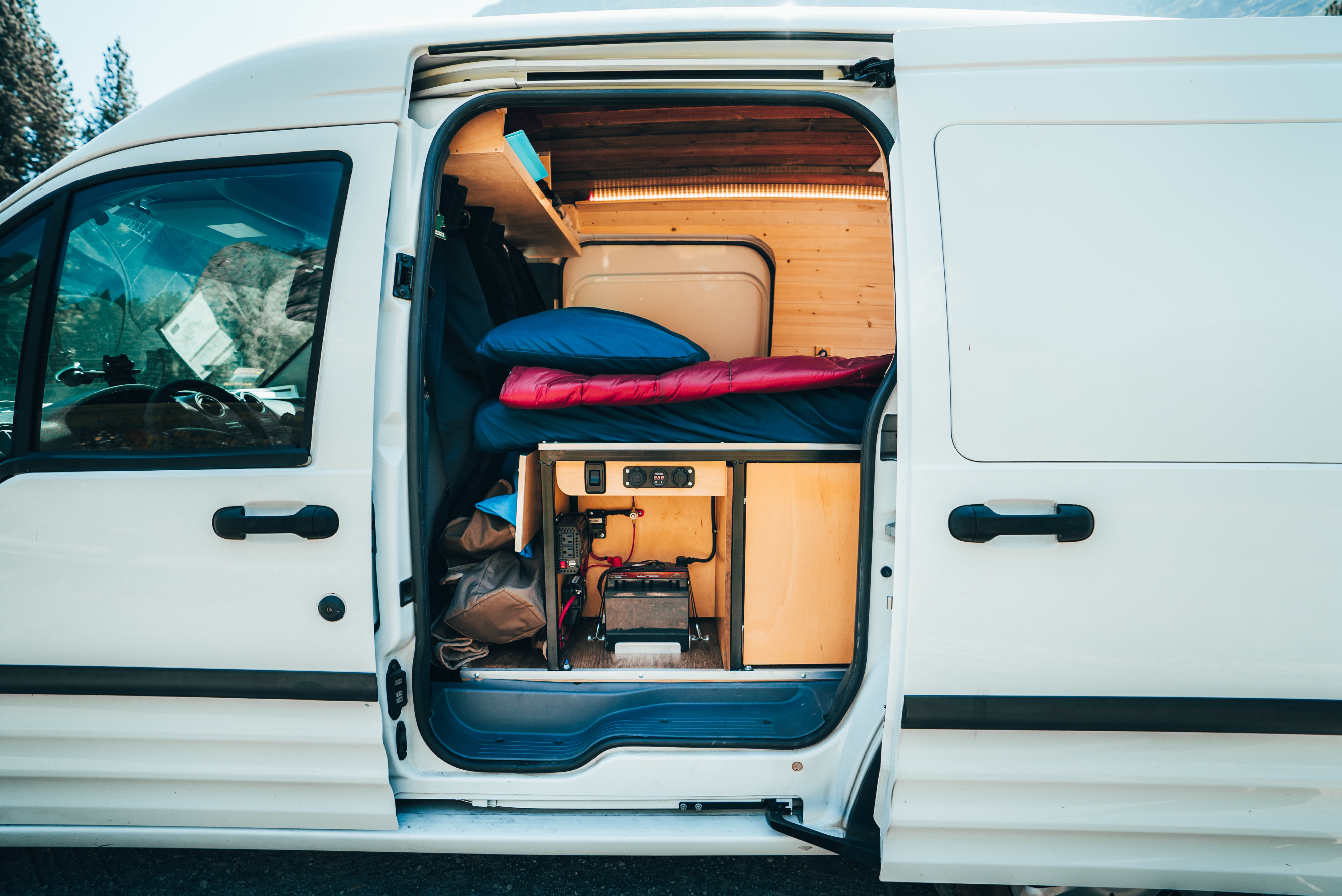 RV rental: Inside a converted camper van, showing the bed, storage, and a robust power setup for mobile living.. Ford Transit 2013