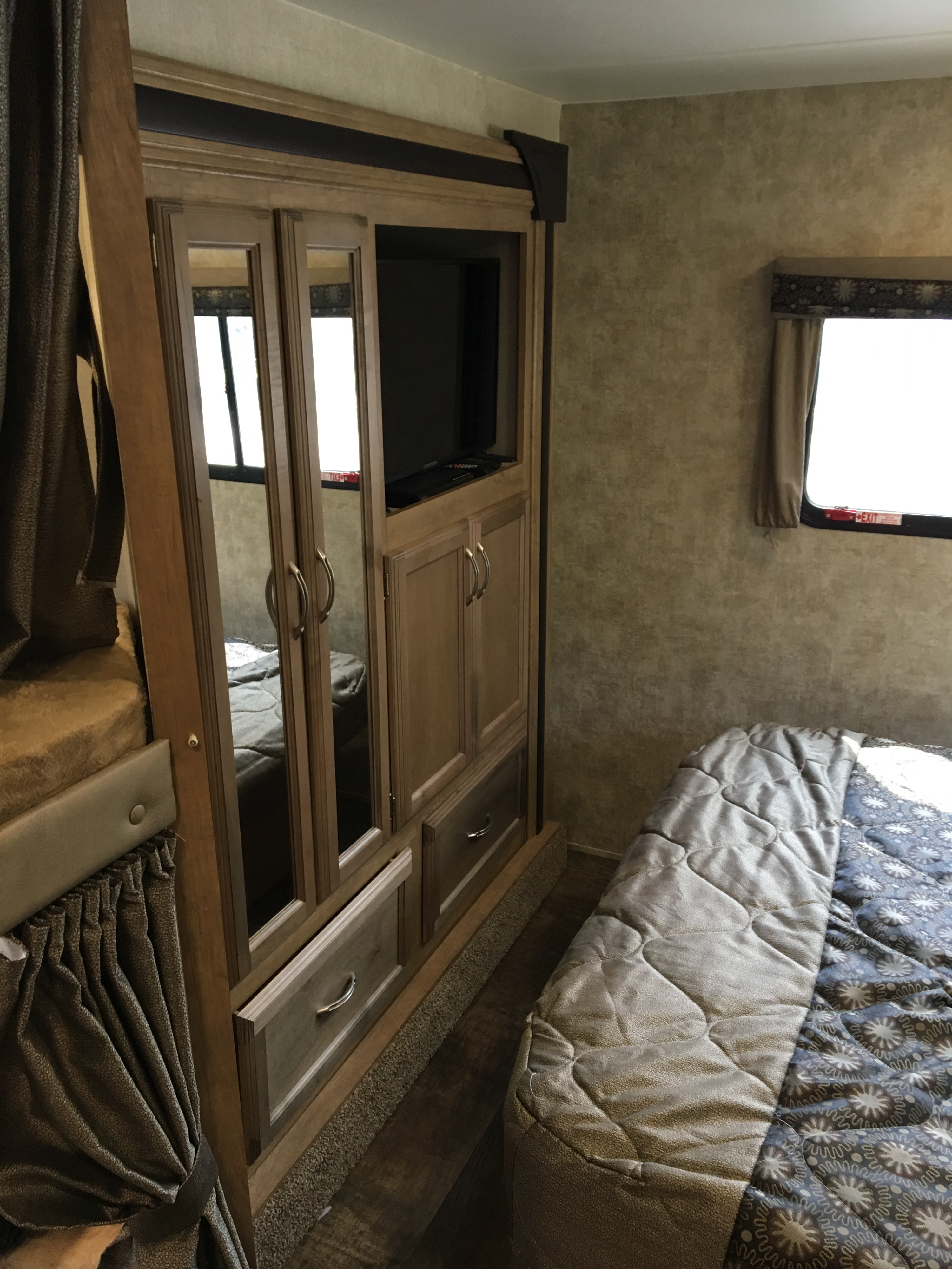 Cozy RV rental bedroom featuring a main bed, bunk, built-in TV, and mirrored storage.. Gulf Stream Conquest 2018