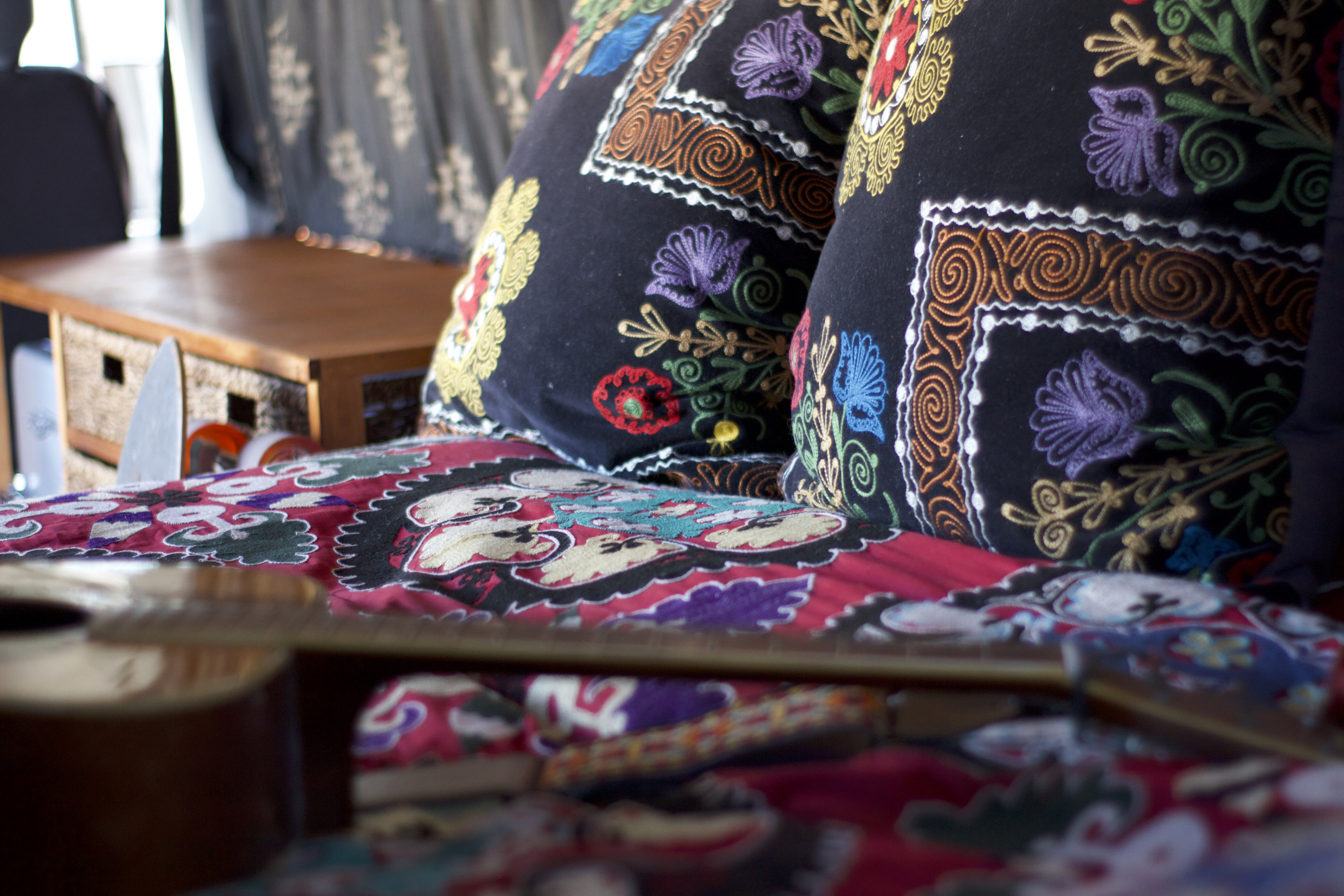 Colorful, cozy RV rental interior with embroidered pillows, patterned bedding, and a guitar for travels.. Mercedes-Benz Sprinter 2005