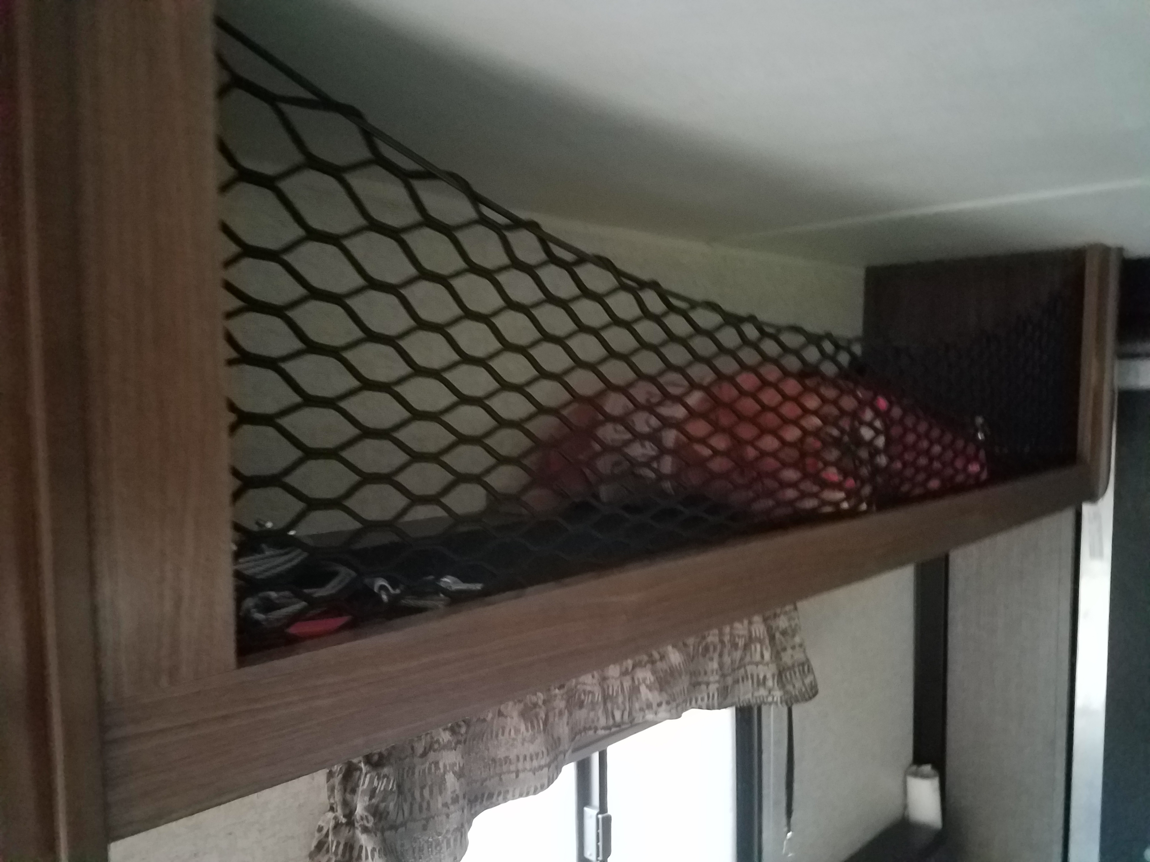 An RV rental features practical overhead storage netting, keeping personal items like a red blanket secure during travel.. Heartland Pioneer 2016