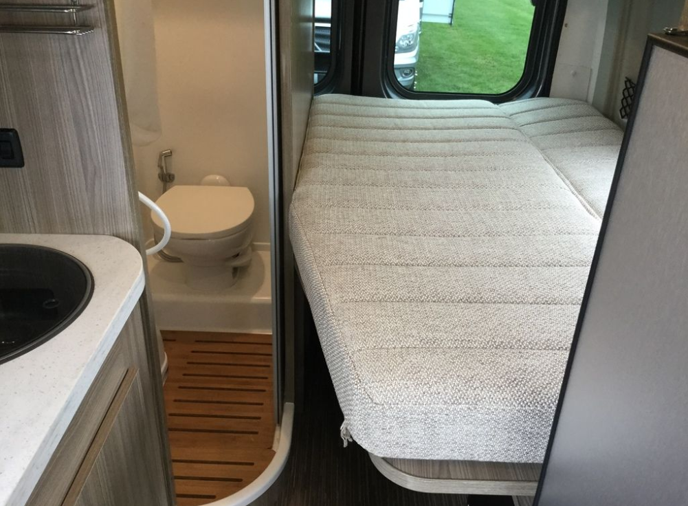 RV rental interior: compact bathroom with toilet, adjacent sink counter, and comfortable sleeping bed.. Winnebago Travato 2019