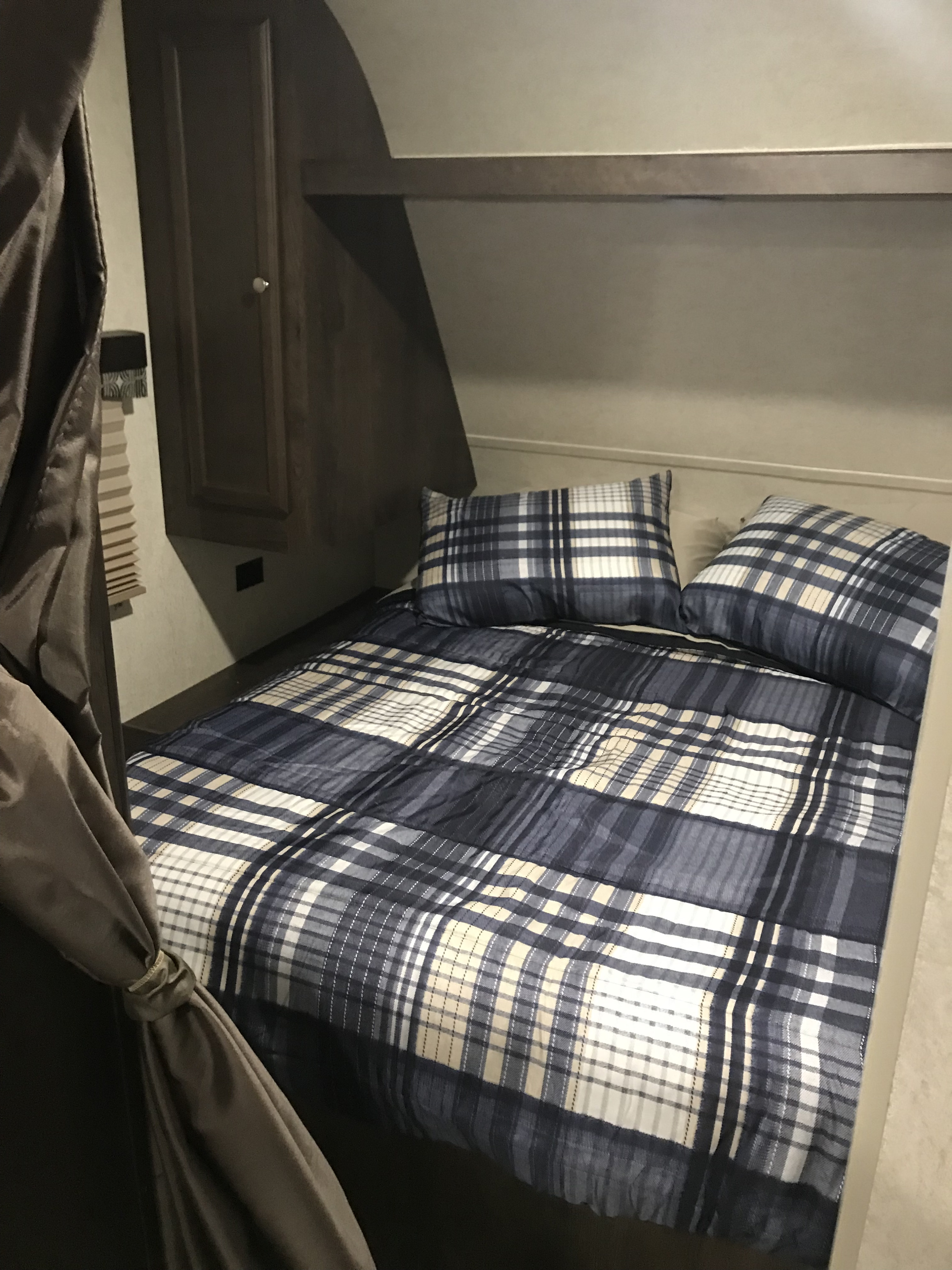 Cozy RV rental bedroom with blue, white, and tan plaid bedding, overhead shelf, and cabinet.. Starcraft Autumn Ridge 27BHS 2018