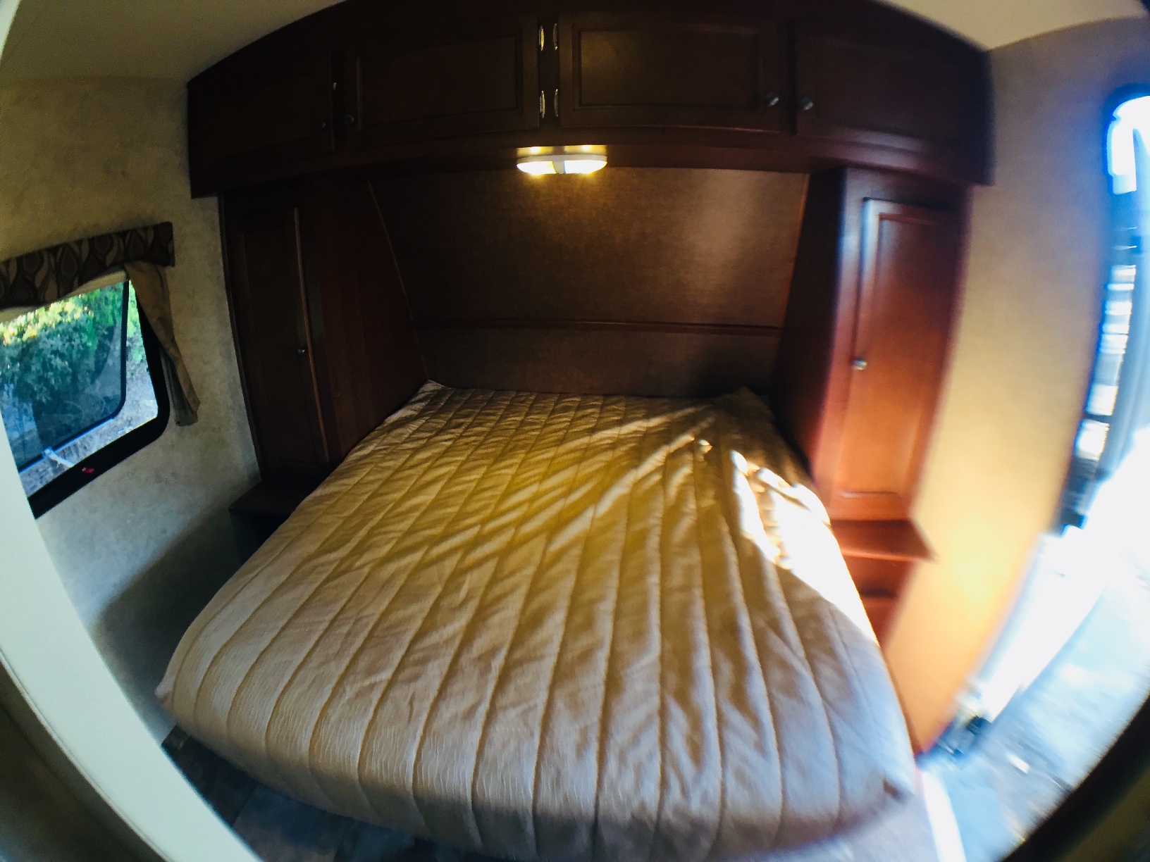RV rental bedroom with quilted bed, built-in storage, and window showcasing outdoor greenery.. R-Vision Trail Lite 23RKS 2014
