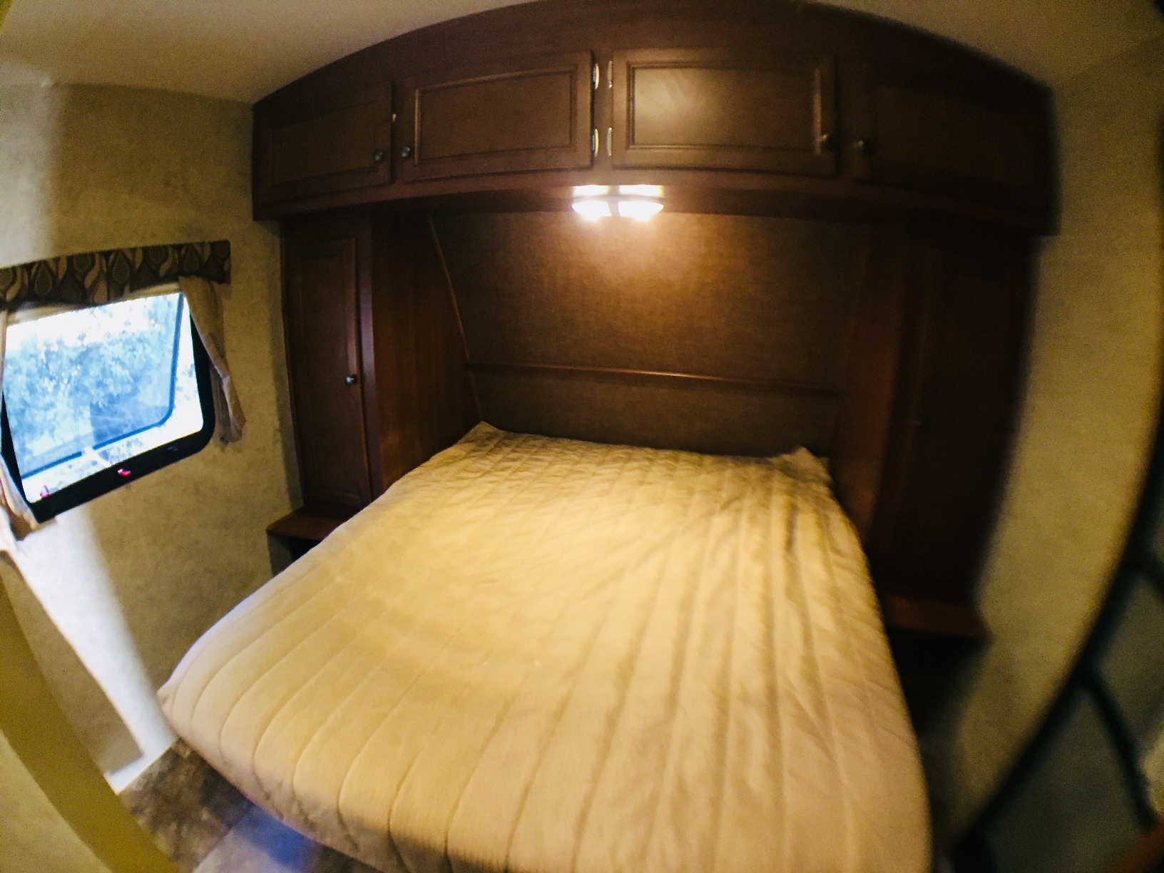 Cozy RV rental bedroom with dark wood cabinets, a queen bed, and a window for comfortable stays.. R-Vision Trail Lite 23RKS 2014