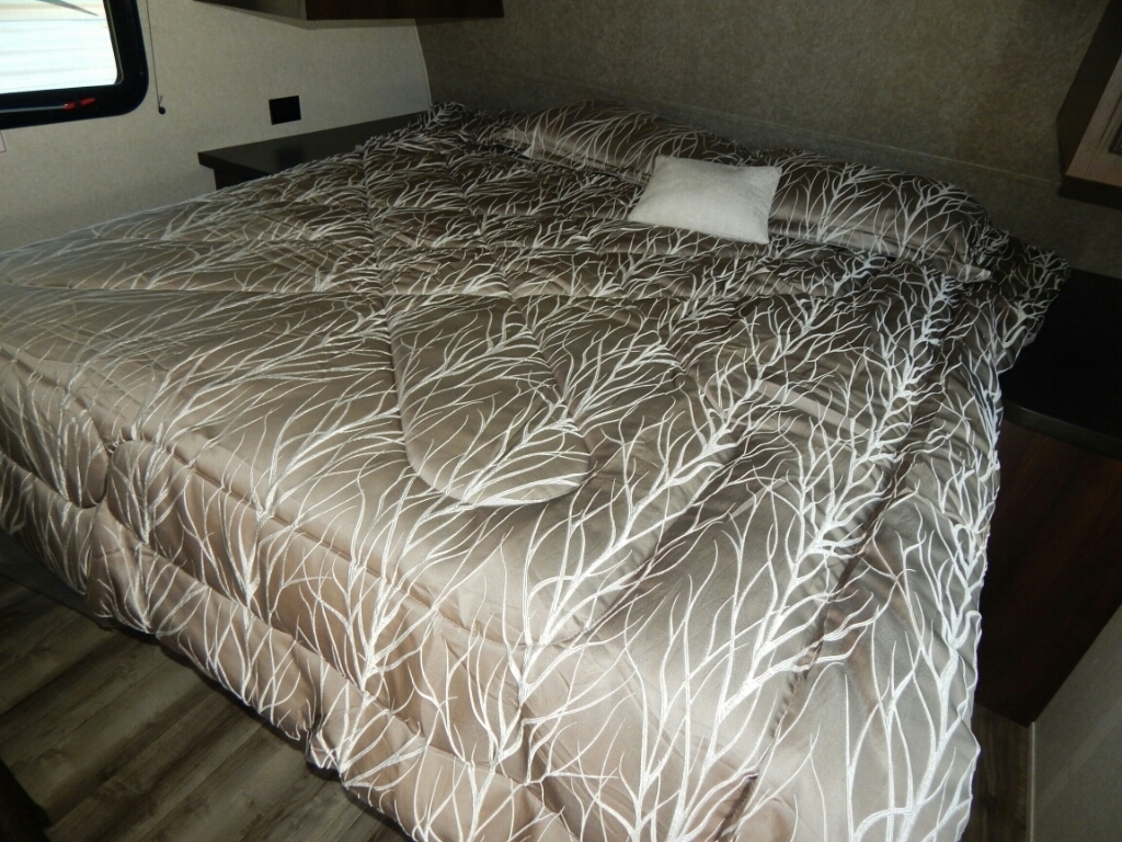 Comfortable RV rental bedroom featuring a bed with a unique brown and white tree-patterned comforter and a small pillow.. Jayco 2019 Jayco 23 foot travel trailer for rent 2019