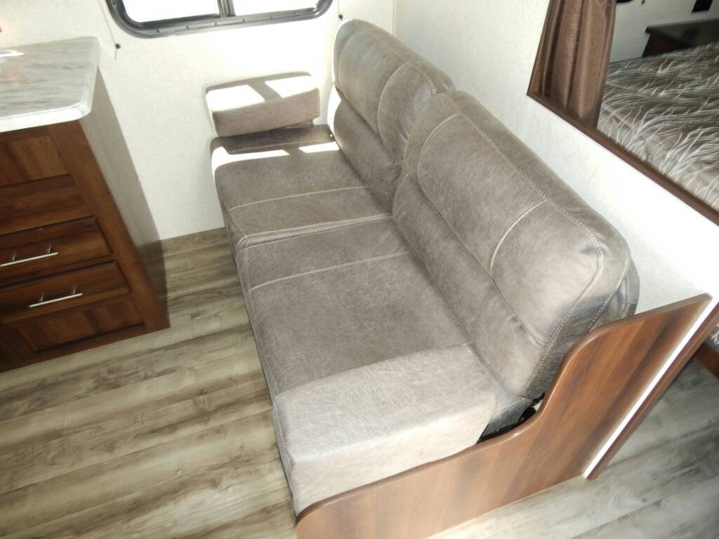 RV rental: Cozy interior featuring a gray convertible sofa, wood cabinet, and window.. Jayco 2019 Jayco 23 foot travel trailer for rent 2019