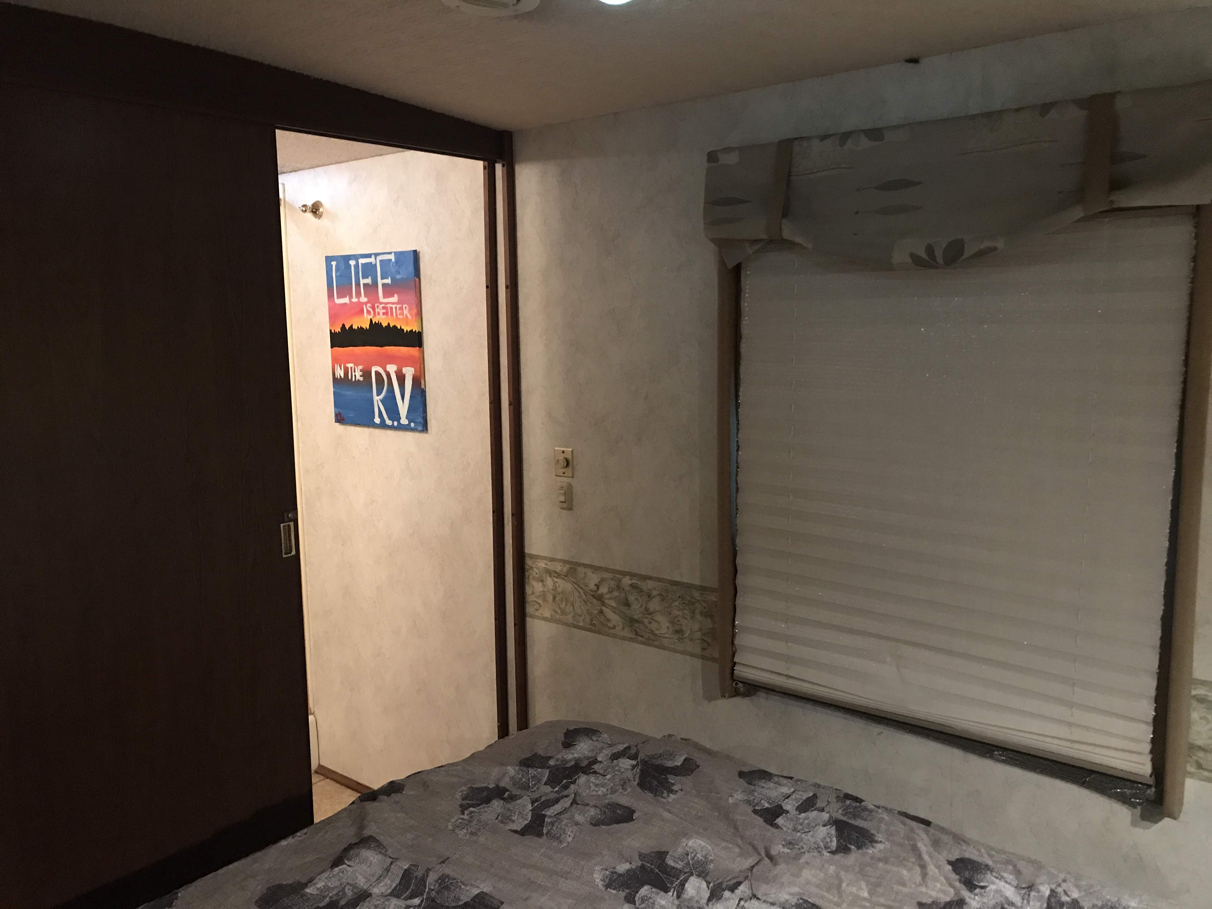 Cozy RV rental interior with a bed, sliding door to another room, and a window with blinds.. Winnebago Journey 2004