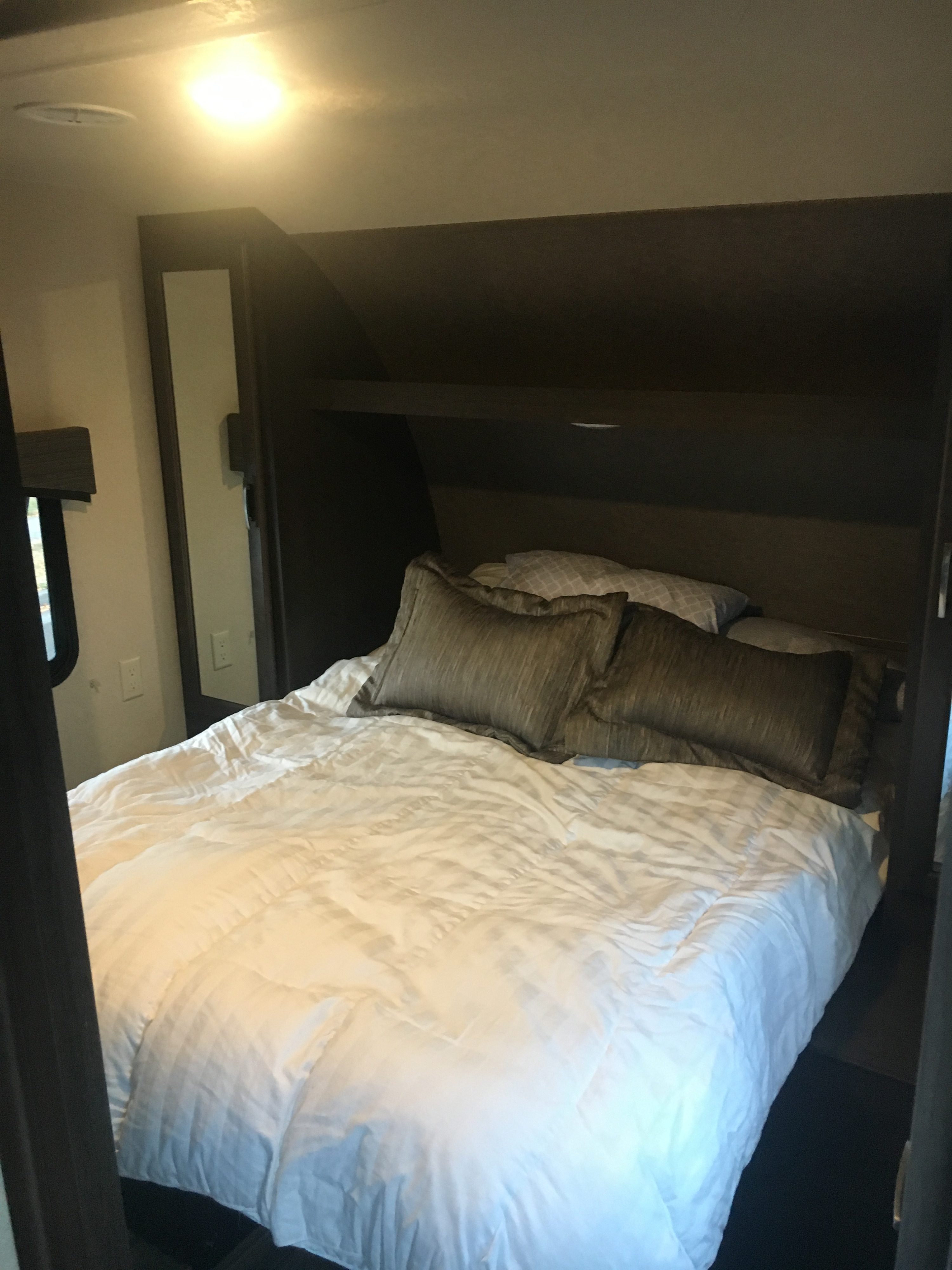 Comfortable RV rental bedroom featuring a cozy bed, built-in headboard with storage, and bright overhead lighting.. Forest River Evo 2016