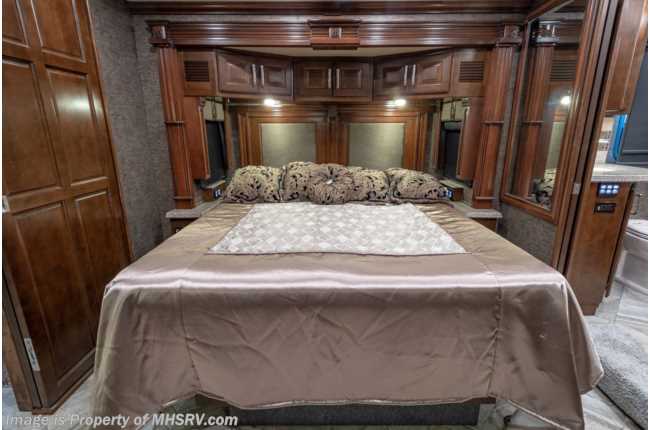Spacious RV rental bedroom featuring a large bed with satin bedding, dark wood cabinetry, and elegant mirrors for a luxurious stay.. American Coach 42m 2016