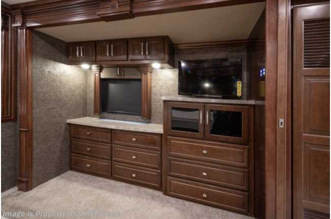 Luxurious RV rental bedroom showcasing rich wood cabinetry, two flat-screen TVs, and built-in storage for ultimate comfort.. American Coach 42m 2016