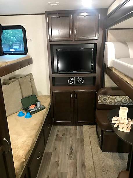 This cozy RV rental interior features bunk beds, a dinette, and an entertainment center, perfect for family adventures.. Jayco Flight 2018