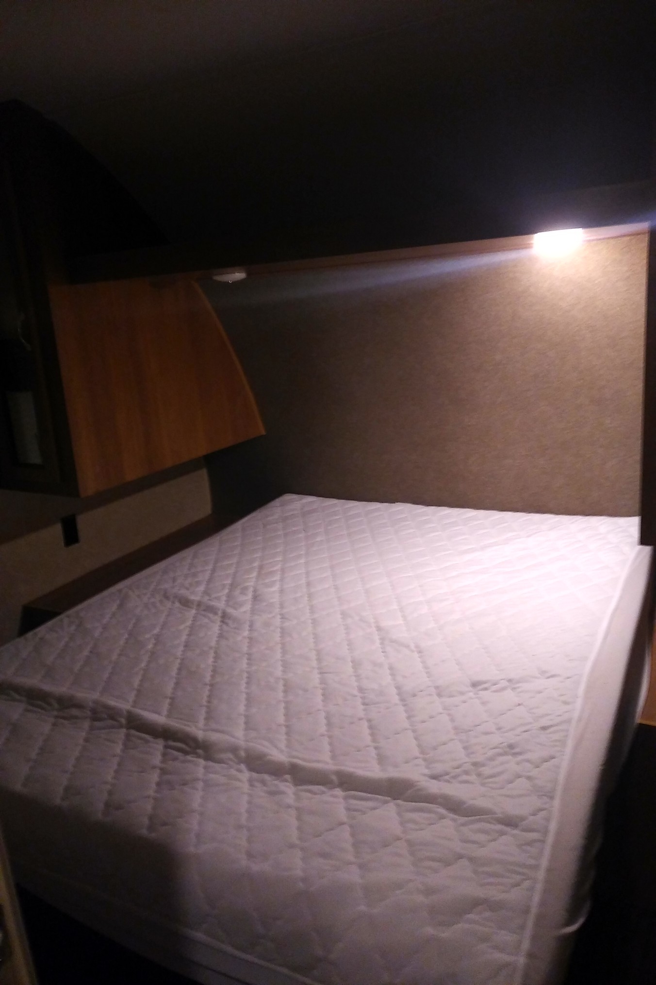 Cozy RV rental sleeping area featuring a quilted mattress and overhead light for a comfortable night.. Catalina 221TBS 2018
