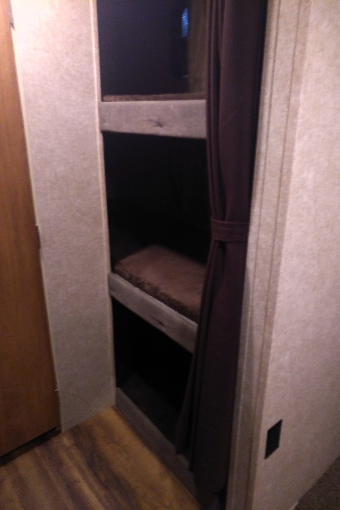 Compact RV rental bunk beds. Cozy sleeping area in a travel trailer interior, with wood floors & a privacy curtain.. Catalina 221TBS 2018
