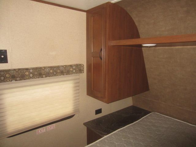 Cozy RV rental bedroom featuring a bed, overhead cabinet storage, and a window with a shade.. Jay Flight 287 BHSW 2016