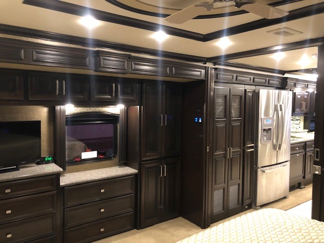 Luxurious dark wood interior of an RV rental, showcasing a modern kitchen, spacious bedroom, and elegant details.. American Coach American Eagle 2016