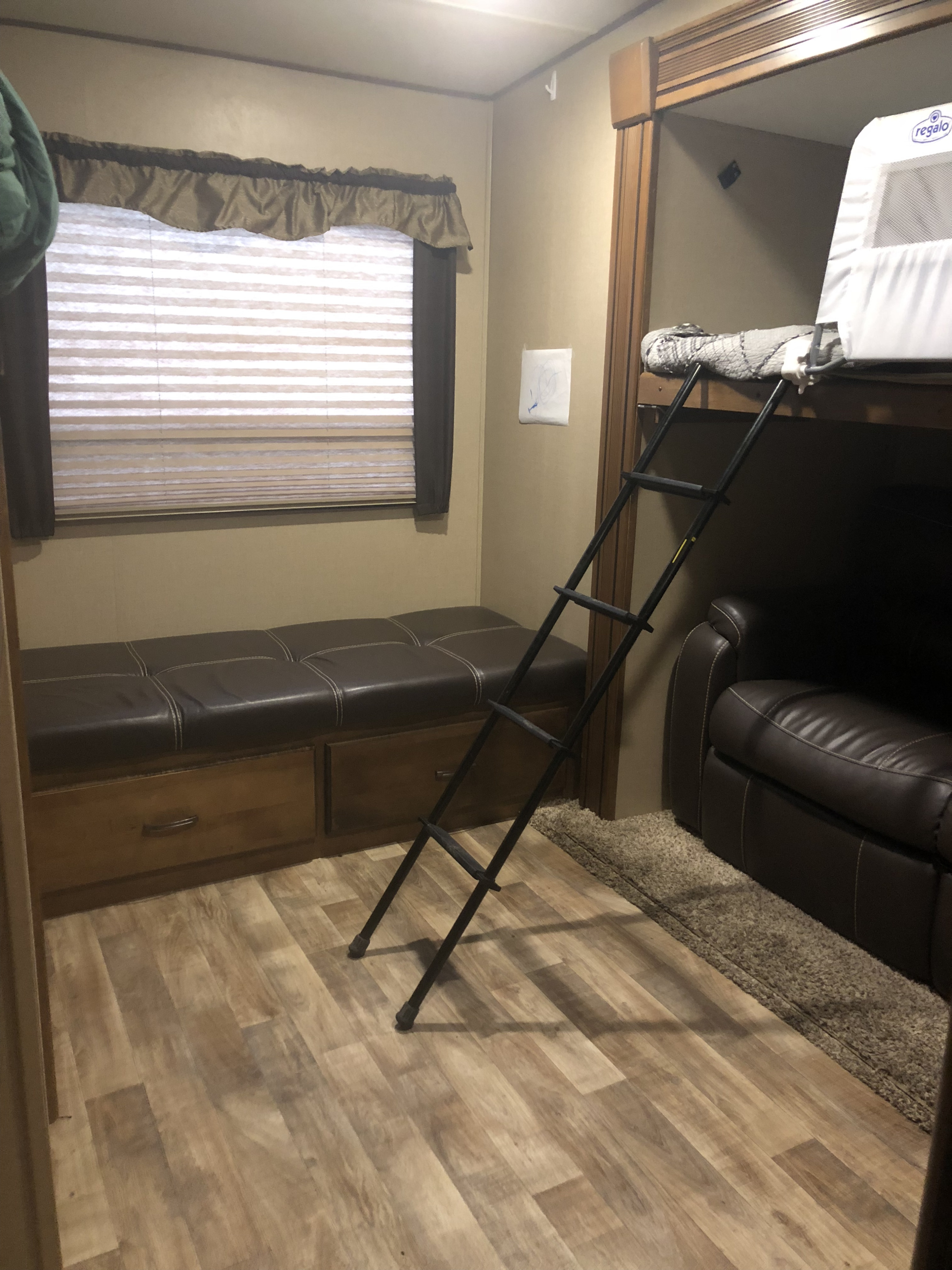 This RV rental interior features a comfy storage bench, a bunk bed with a ladder, and a recliner. Perfect for family adventures.. Grand Design Reflection 2015