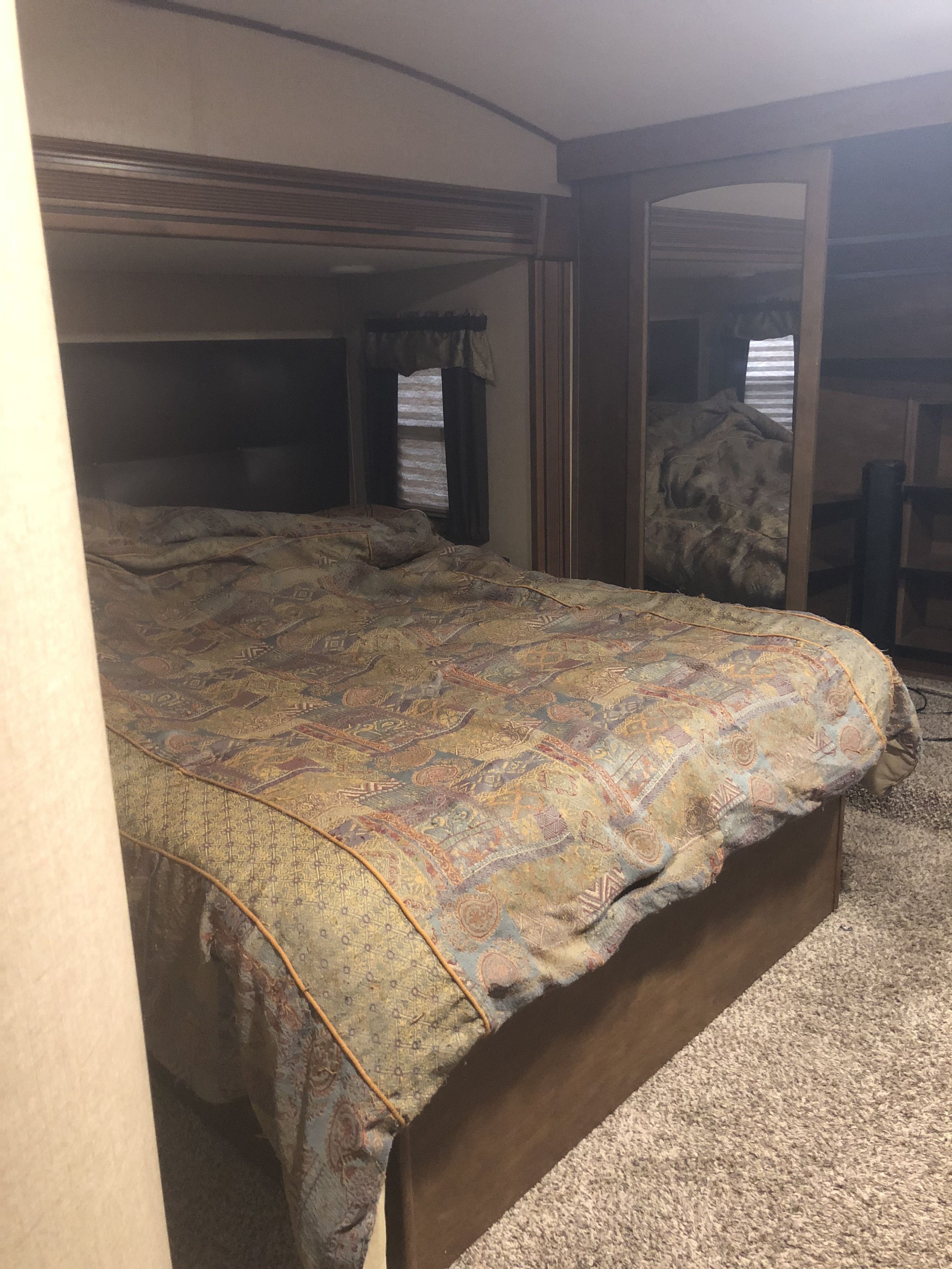 Cozy RV bedroom with a patterned bed and mirrored closet doors, ideal for your next RV rental.. Grand Design Reflection 2015