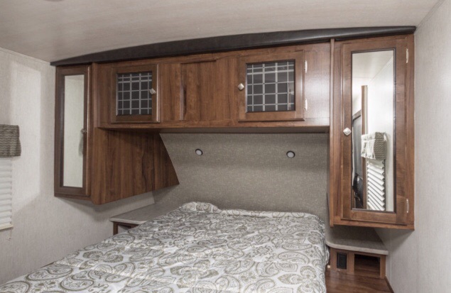 RV rental interior: cozy bedroom featuring overhead storage cabinets, a comfortable bed, and mirrored closet doors.. Heartland Wilderness 2018