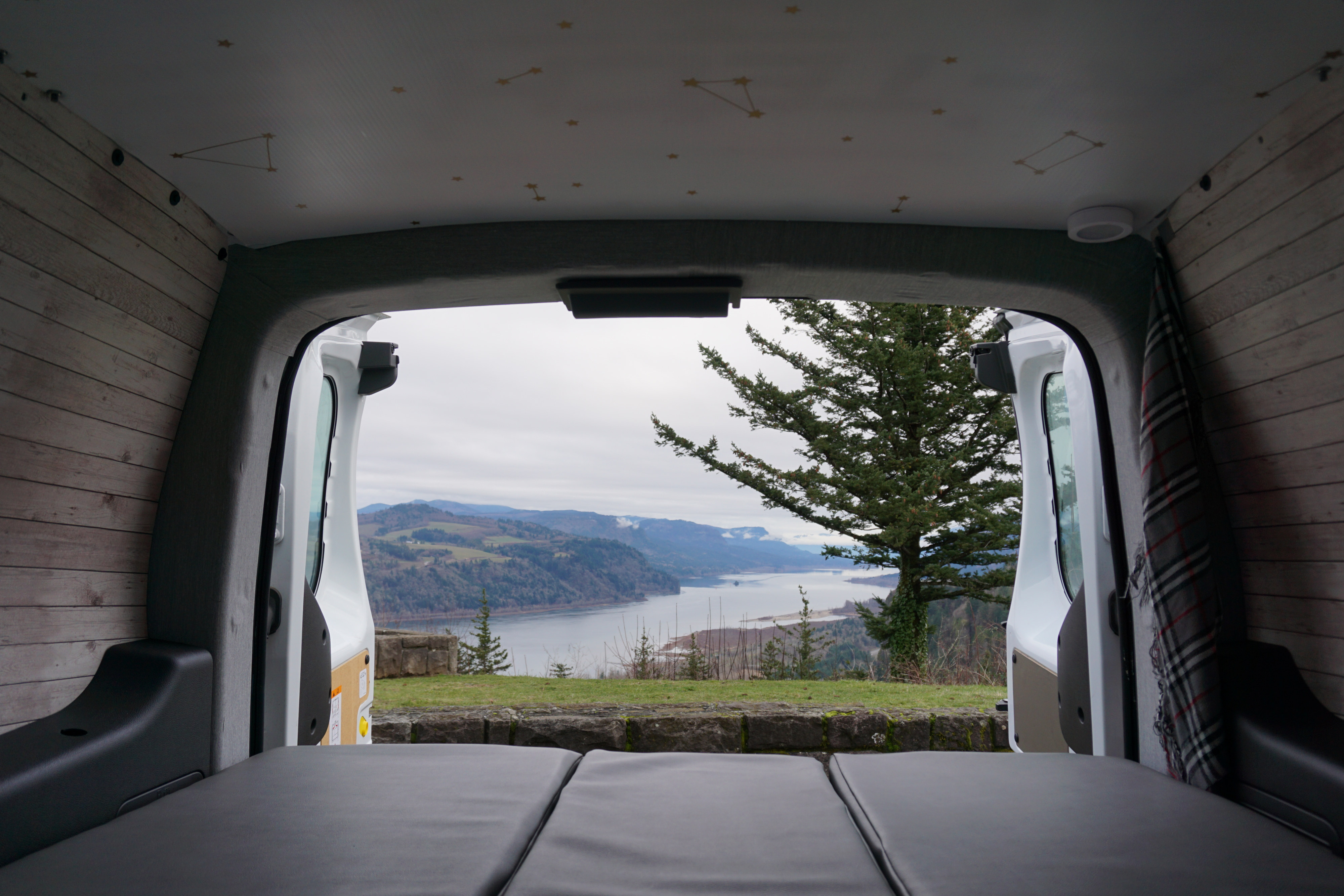 Cozy RV rental van interior overlooks a spectacular scenic view: a river, mountains, and trees. Ideal for nature travel.. Ford Transit Custom 2017
