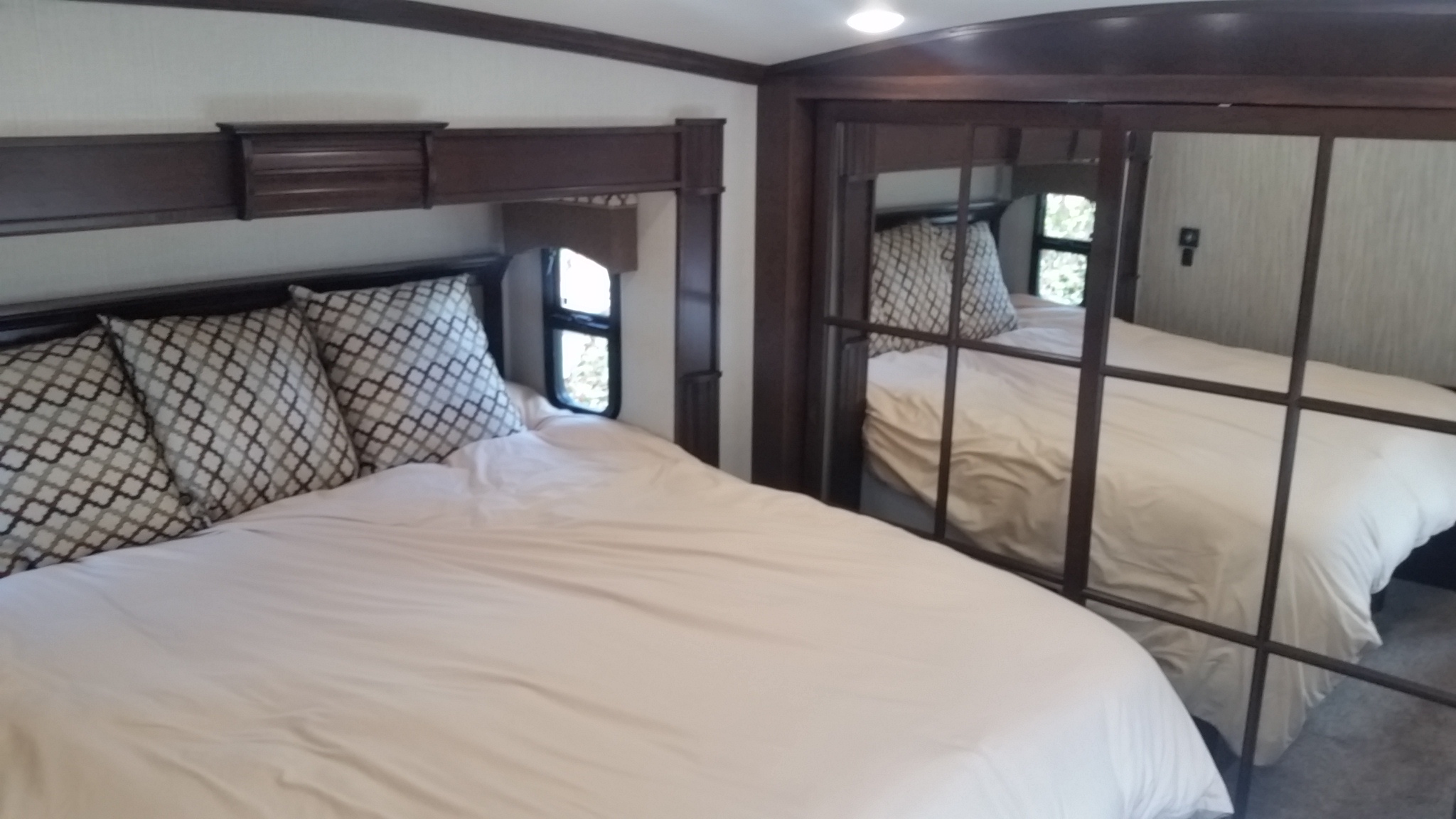 Spacious RV rental bedroom featuring a large bed with patterned pillows and a mirrored closet for comfortable travel.. Forest River Cardinal 2017