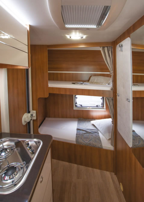 This RV rental interior shows two bunk beds, a small window, and a compact kitchen with a stove, ideal for camper travel.. RIMOR SEAL 9 2018