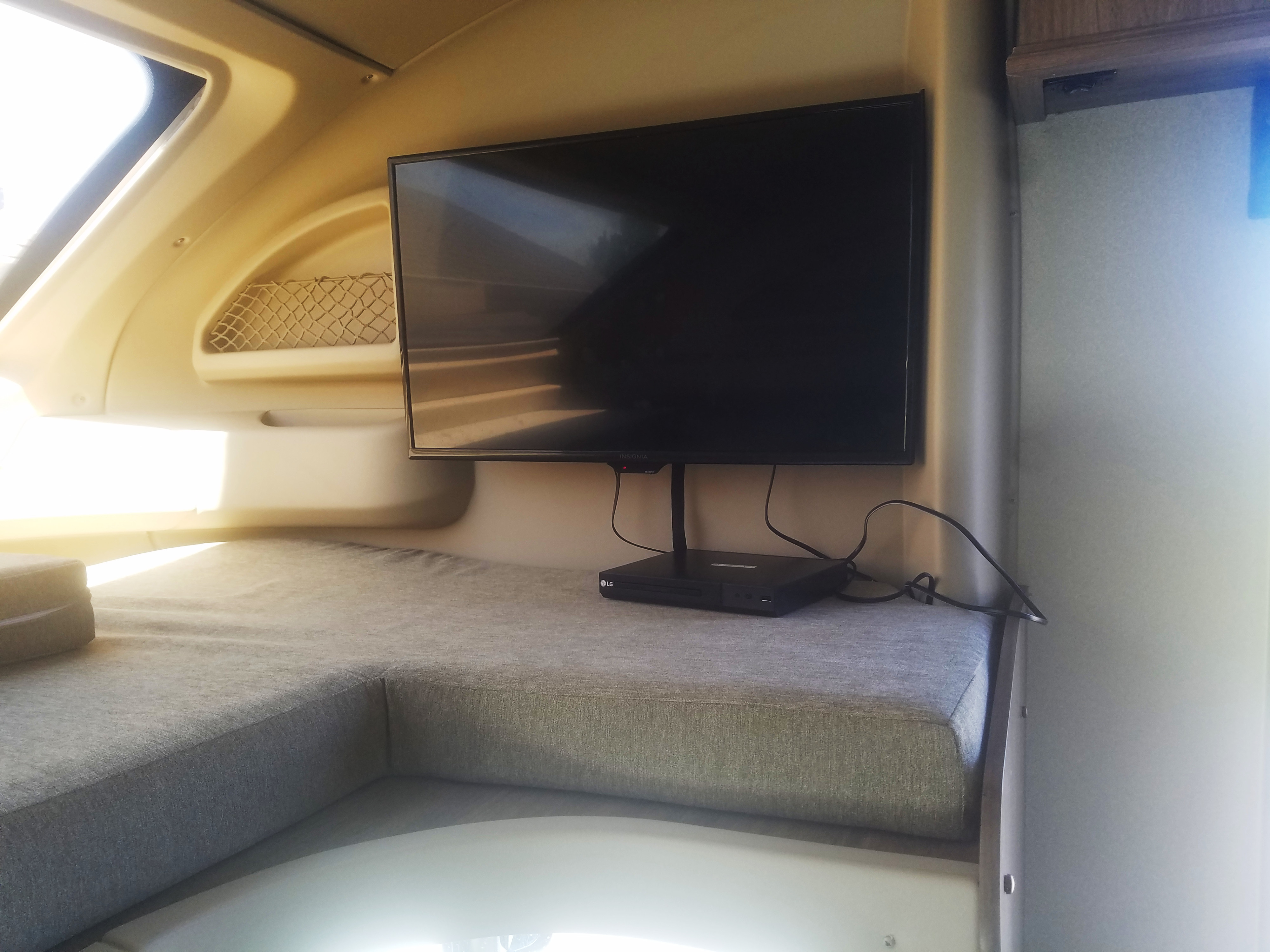 Cozy RV rental interior with a TV, LG media player, and L-shaped grey upholstered bed/seating.. Jayco Envoy 2018