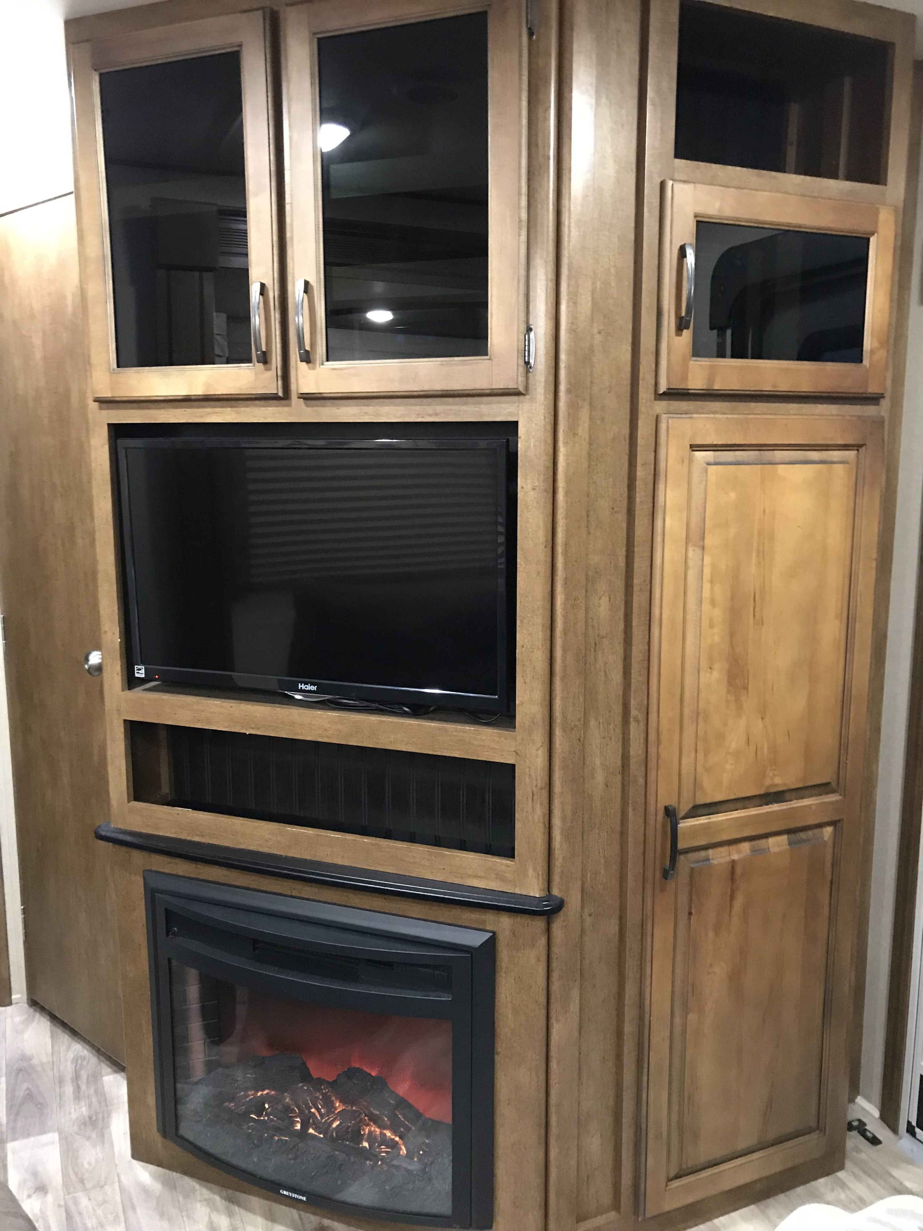 RV rental interior featuring a built-in entertainment center with a TV, electric fireplace, and ample wood storage cabinets.. Grand Design Reflection 2015