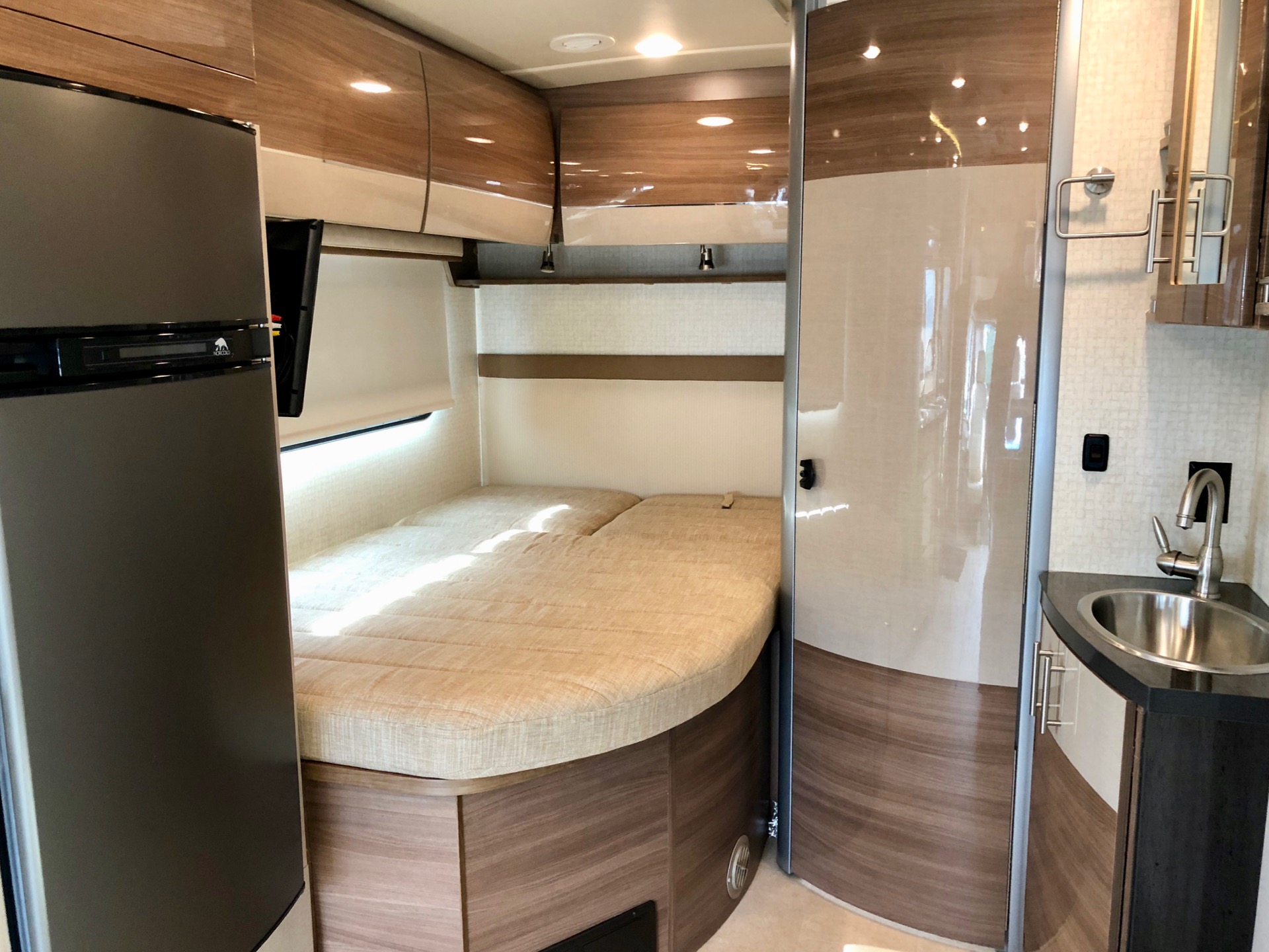 Experience RV rental comfort! Spacious motorhome interior featuring a bed, fridge, and compact kitchen area.. Itasca Navion 24J 2016