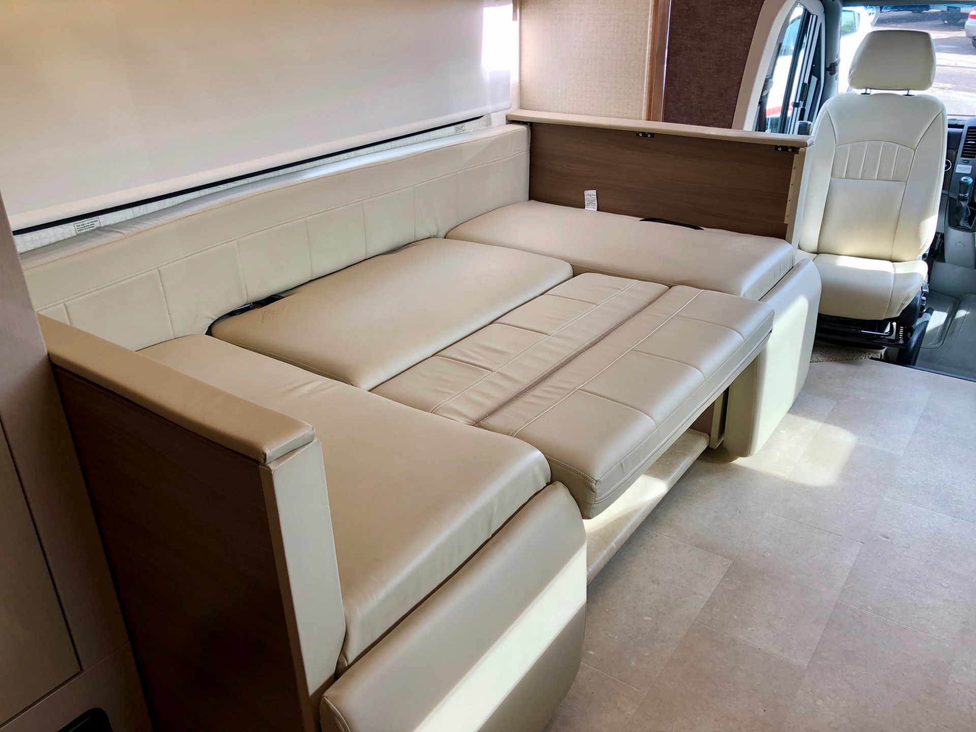 RV rental interior: Spacious, beige, pull-out sofa converts to a bed for comfortable travel in this camper van.. Itasca Navion 24J 2016