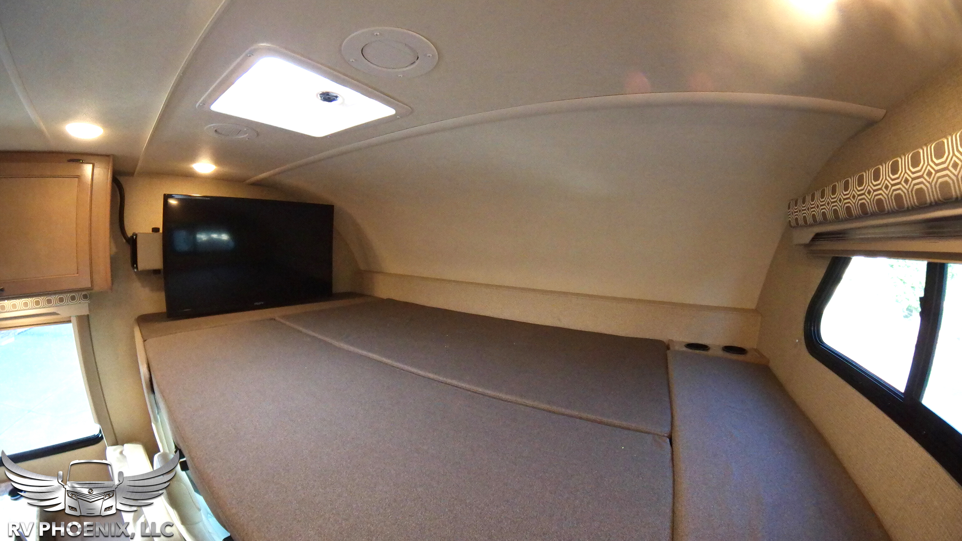 This RV rental features a cozy over-cab bunk bed with a mounted TV, skylight, and window, perfect for comfortable sleeping.. Thor Motor Coach Four Winds 2019