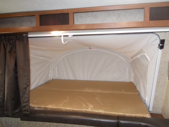 RV rental: Pop-out bed in a camper, featuring a light brown mattress, canvas walls, and dark privacy curtains.. Jayco Jay Feather 2018