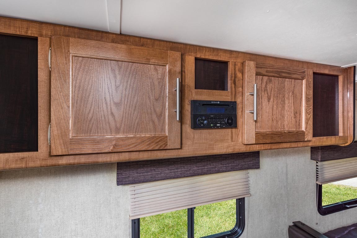 RV rental interior featuring overhead wooden cabinets, a built-in stereo system, and windows with blinds.. Gulf Stream 199DD 2019