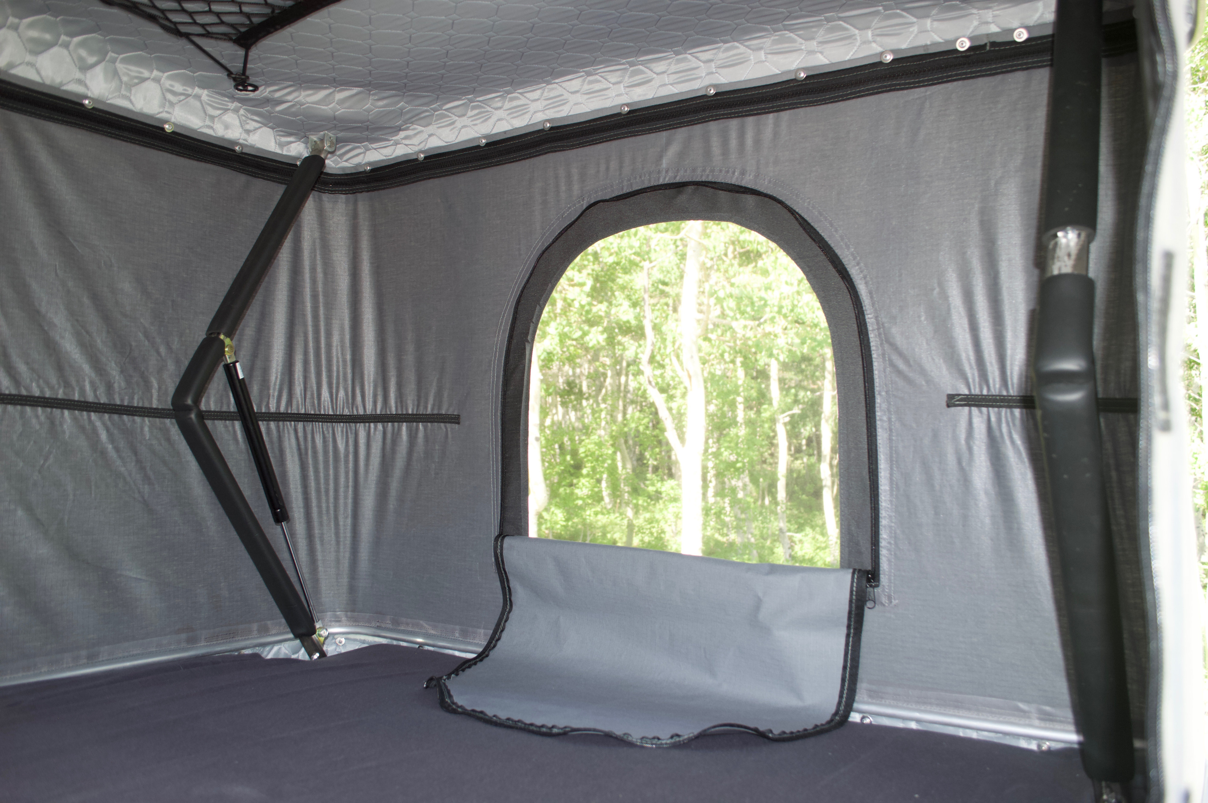 RV rental interior shows a cozy sleeping area with a scenic arched window and mosquito net, perfect for nature views.. Ram Promaster City 2018