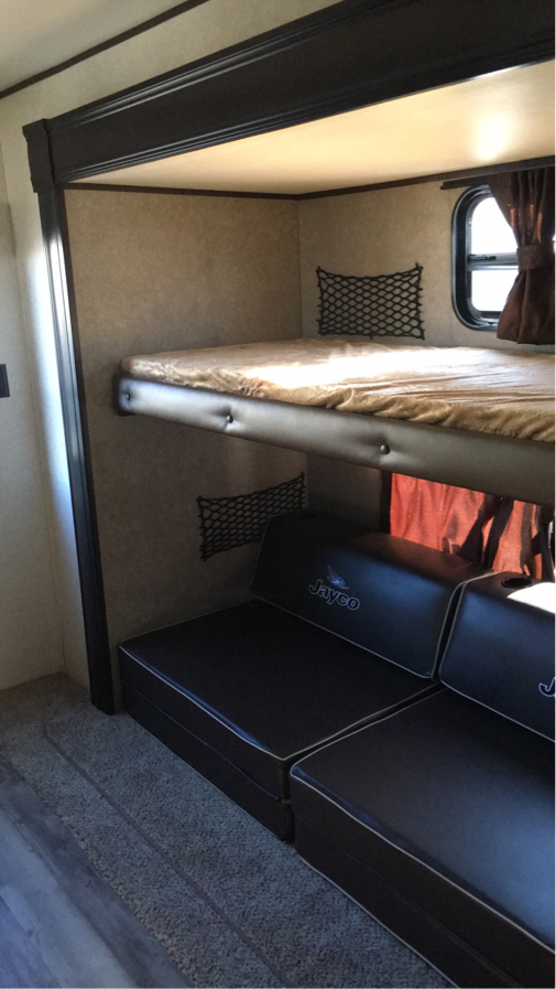 This RV rental features a comfortable bunk bed setup with Jayco seating and storage nets, perfect for family travel.. Jayco Flight 2018
