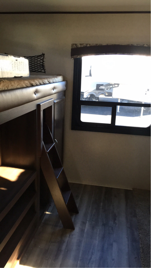 RV rental interior: Bunk beds with a wooden ladder and window, offering compact sleeping space.. Jayco Flight 2018