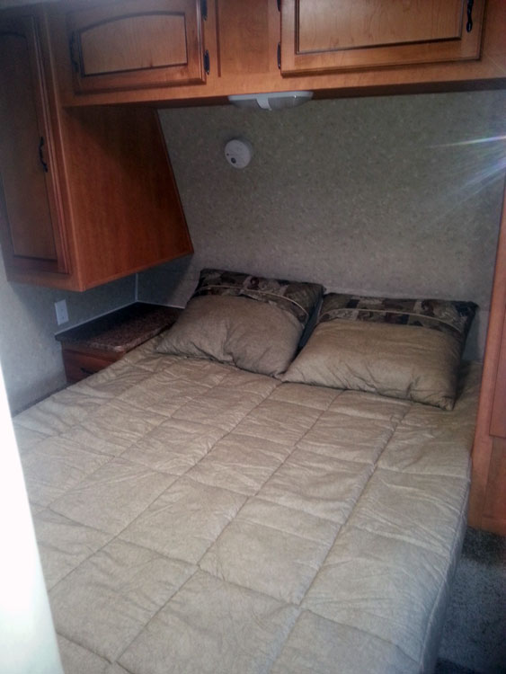 Cozy RV rental bedroom with a comfortable bed and overhead storage cabinets, ideal for a good night's sleep.. Palomino Puma 28 BHS 2011