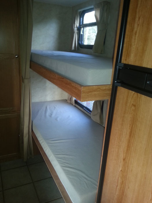 RV rental interior: Stacked bunk beds with mattresses, a window, and curtains, perfect for family sleeping accommodations.. R-Vision TS 24BH 2011