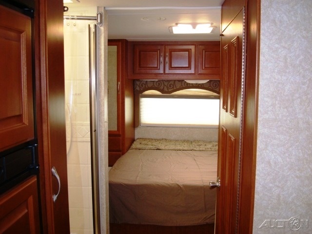 RV rental interior: A compact bedroom with bed, overhead cabinets, and an adjacent shower.. Four Winds Chateau 2008