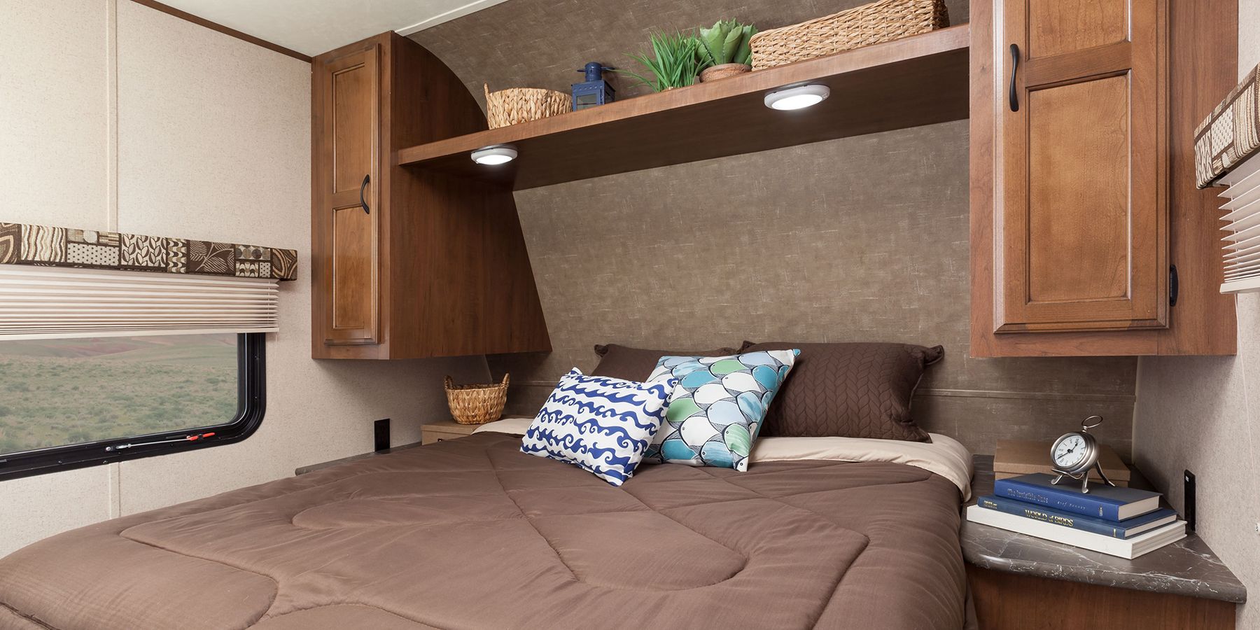 This cozy RV rental bedroom offers a comfortable bed, overhead storage, and a scenic window view, ideal for travel.. Jayco Jay Flight 2016