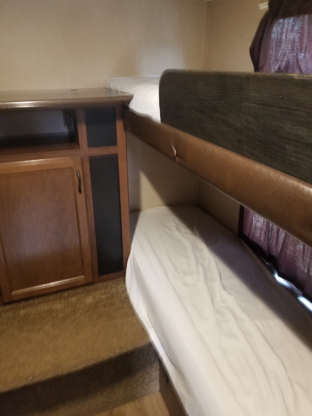 Compact RV rental interior featuring a wooden cabinet and comfortable bunk beds with white sheets and a padded upper rail.. Jayco White Hawk Ultra Lite 2015