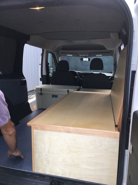 RV rental: Van interior with custom bed/storage, Yeti cooler, and blue floor mat.. ram promaster city 2018
